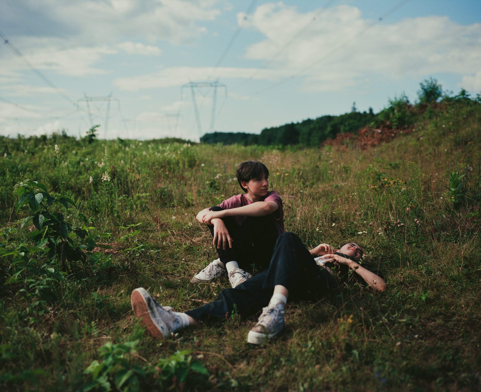 Joseph Engal as Bastien and Sara Montpetit as Chloé lay on the grass 'Falcon Lake'