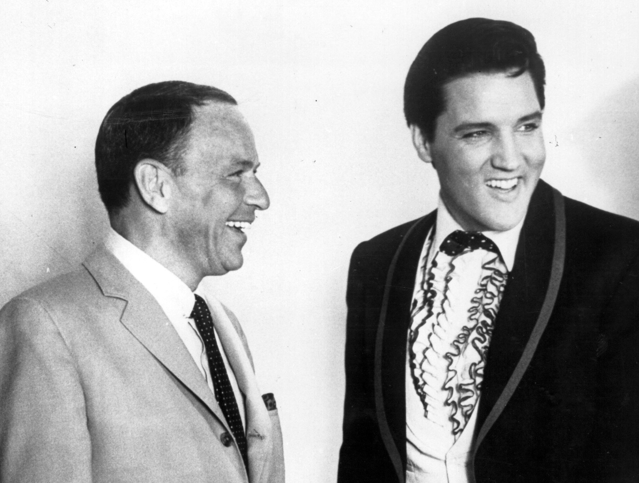 A black and white picture of Frank Sinatra and Elvis wearing suits and smiling.