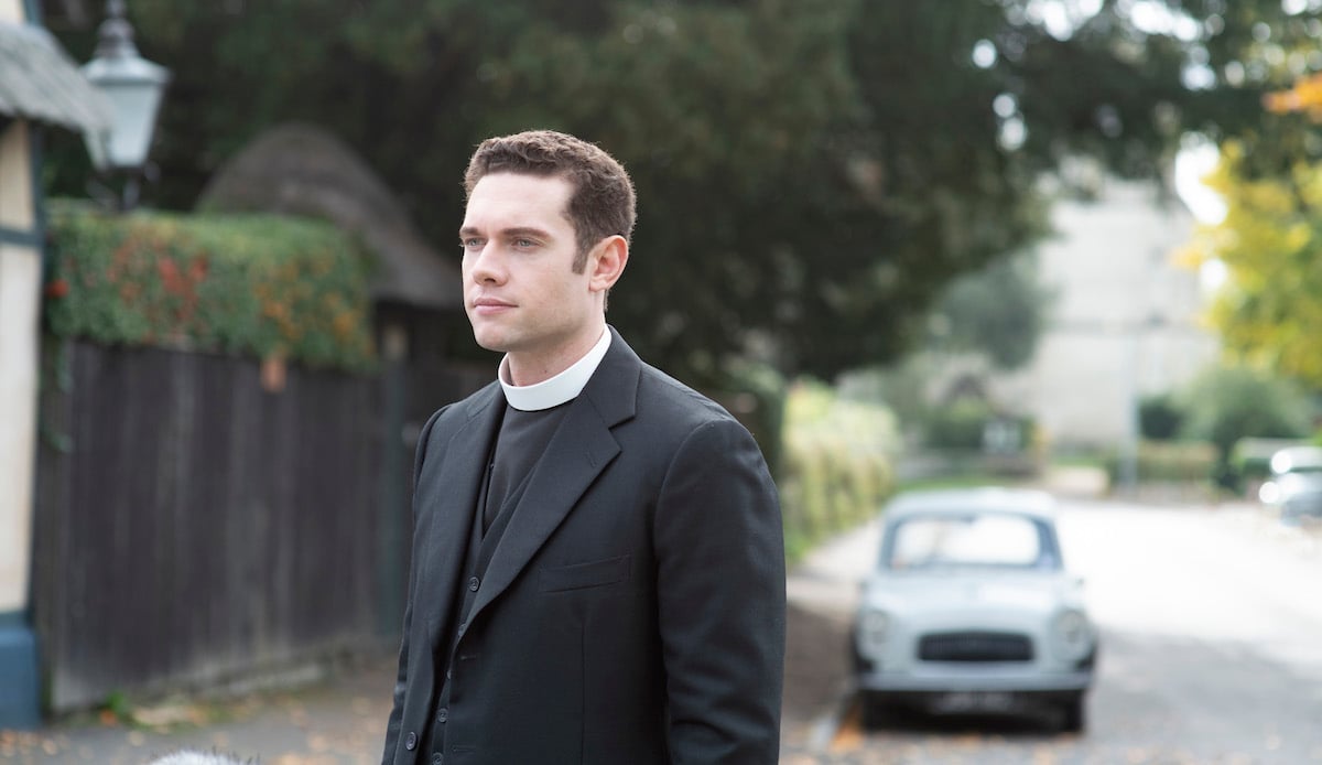 Tom Brittney as Will Davenport, wearing a black jacket and priest's collar, in season 6 of 'Grantchester' on PBS