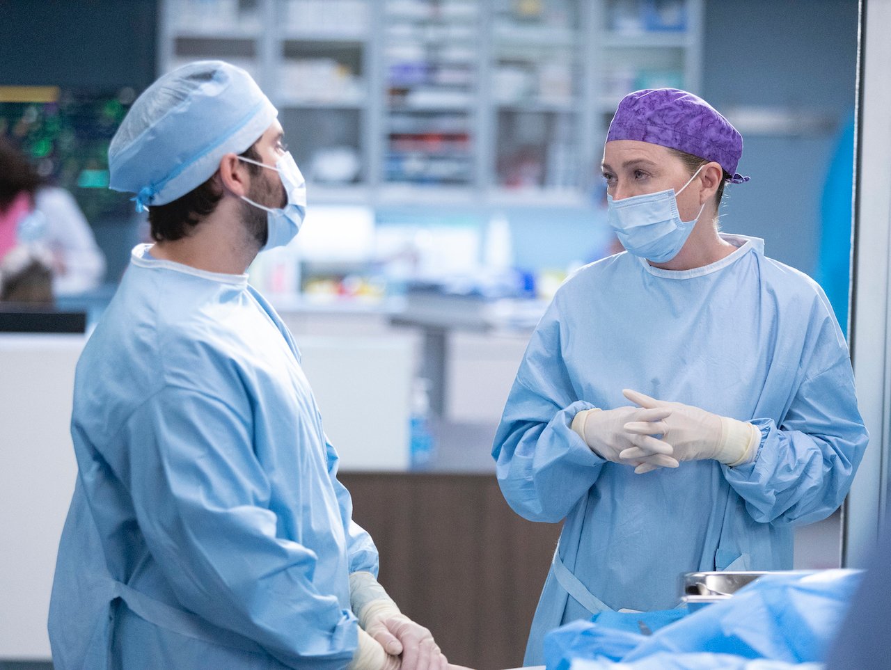 Jake Borelli as Levi Schmitt and Ellen Pompeo as Meredith Grey look at each other in scrubs in 'Grey's Anatomy'.