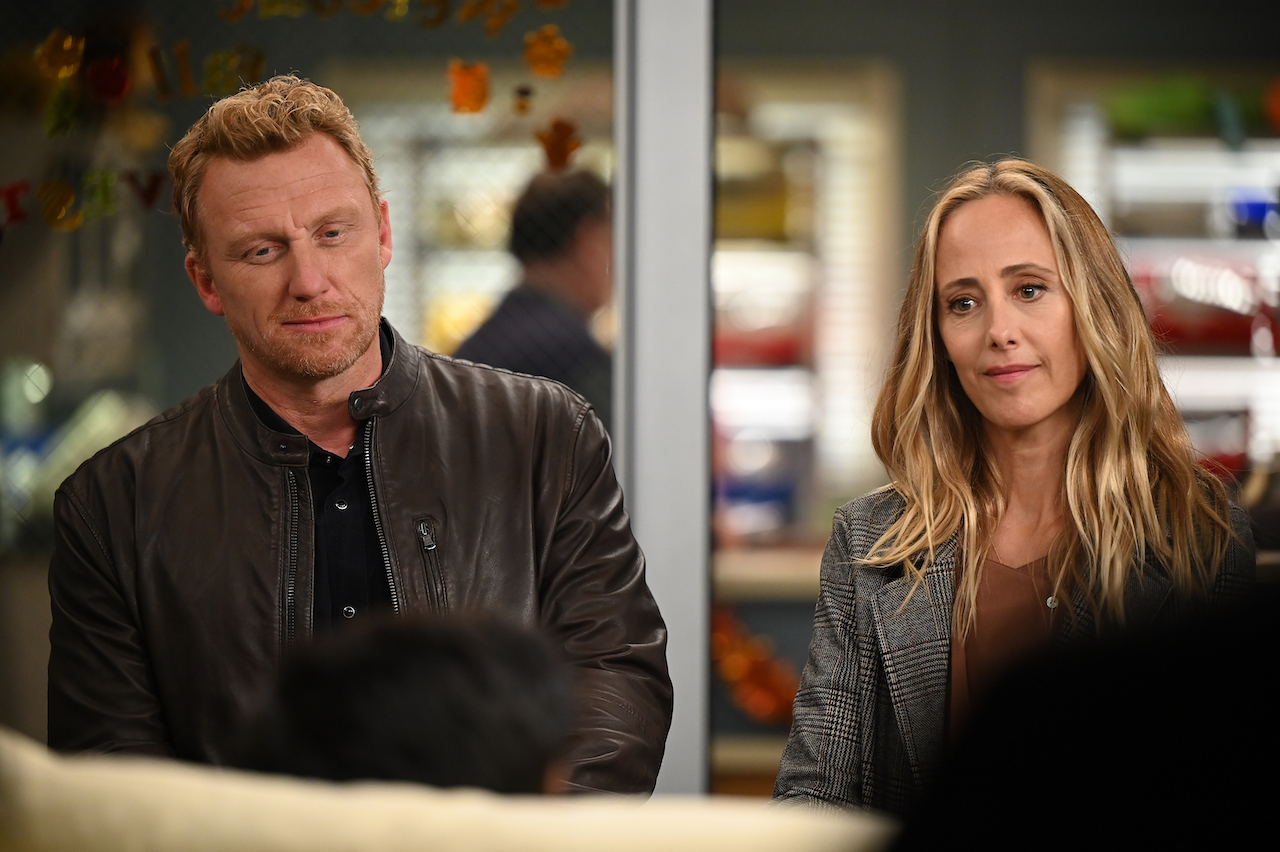 Owen (Kevin McKidd) and Teddy (Kim Raver) stand next to each other in casual clothes in the hospital in 'Grey's Anatomy'.