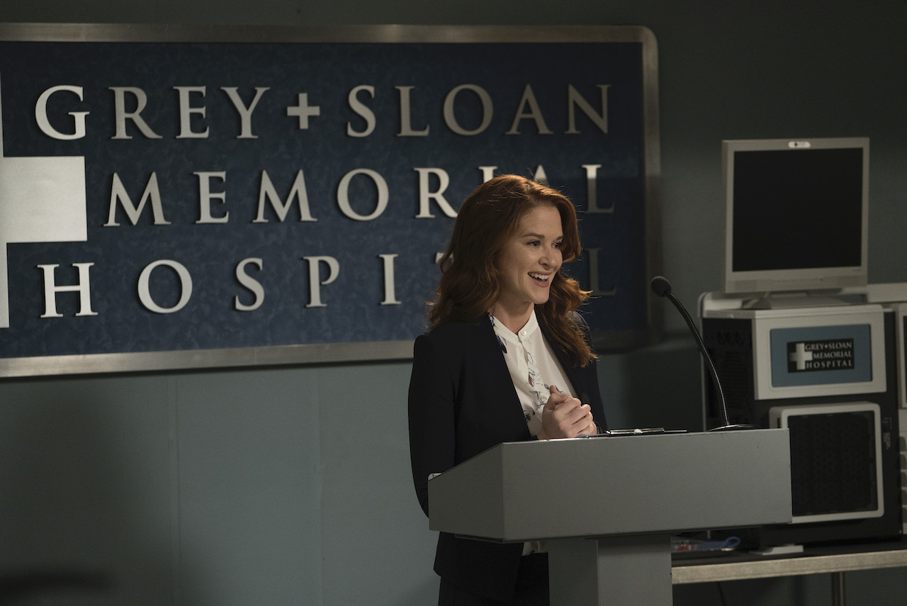 Sarah Drew as April Kepner stands at a podium in 'Grey's Anatomy'.