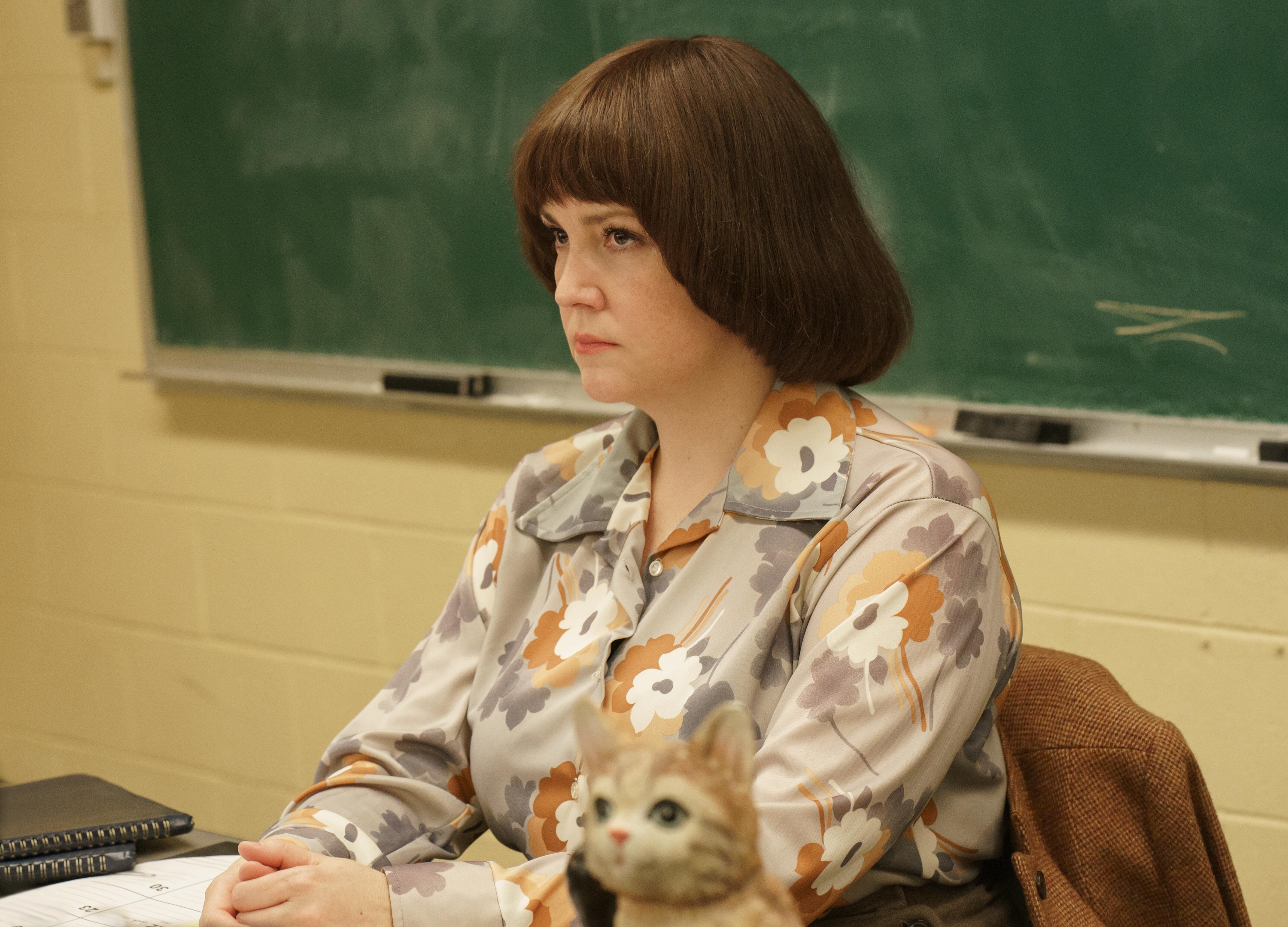 Melanie Lynskey sits in a teacher chair angrily fuming as Betty Gore in 'Candy' on Hulu