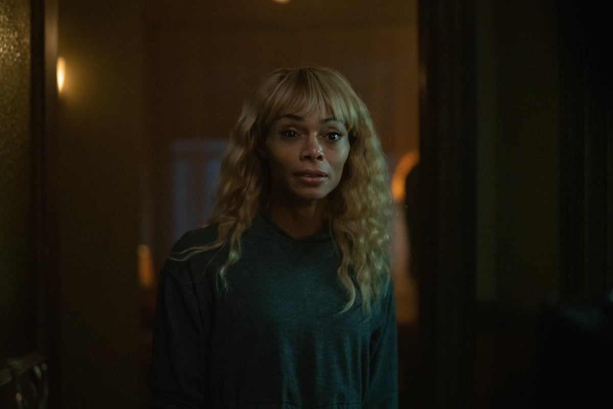 Jasmine Davis as her 'The Chi' character Imani wearing blonde hair and a sweater with a startled look on her face