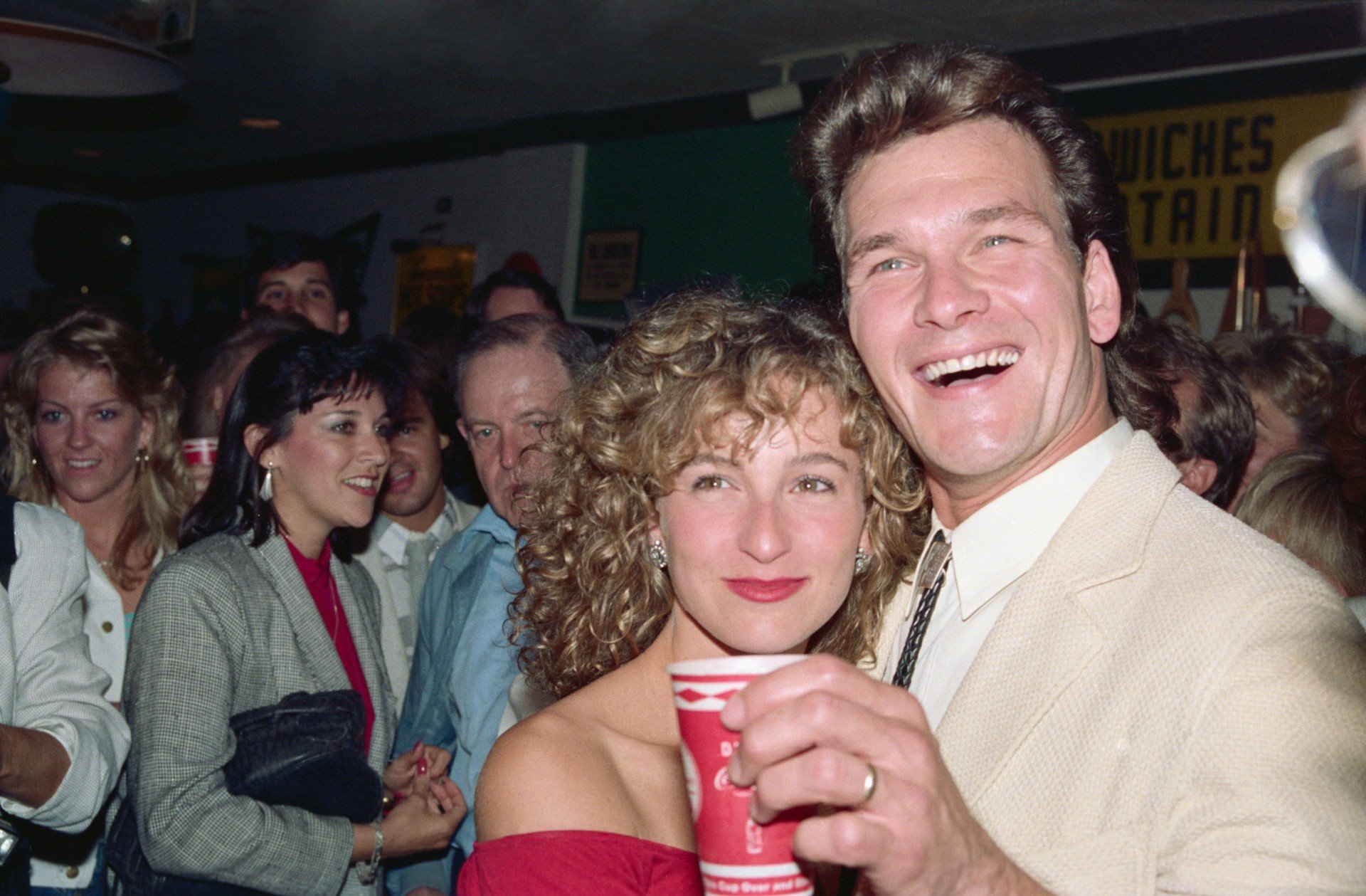 Jennifer Grey and Patrick Swayze laugh together at a media event.