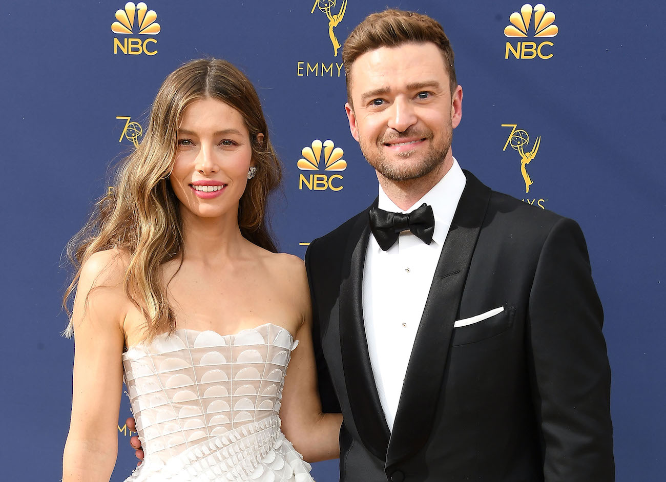 Jessica Biel wearing a white outfit and posing next to Justin Timberlake, who is wearing a black tuxedo