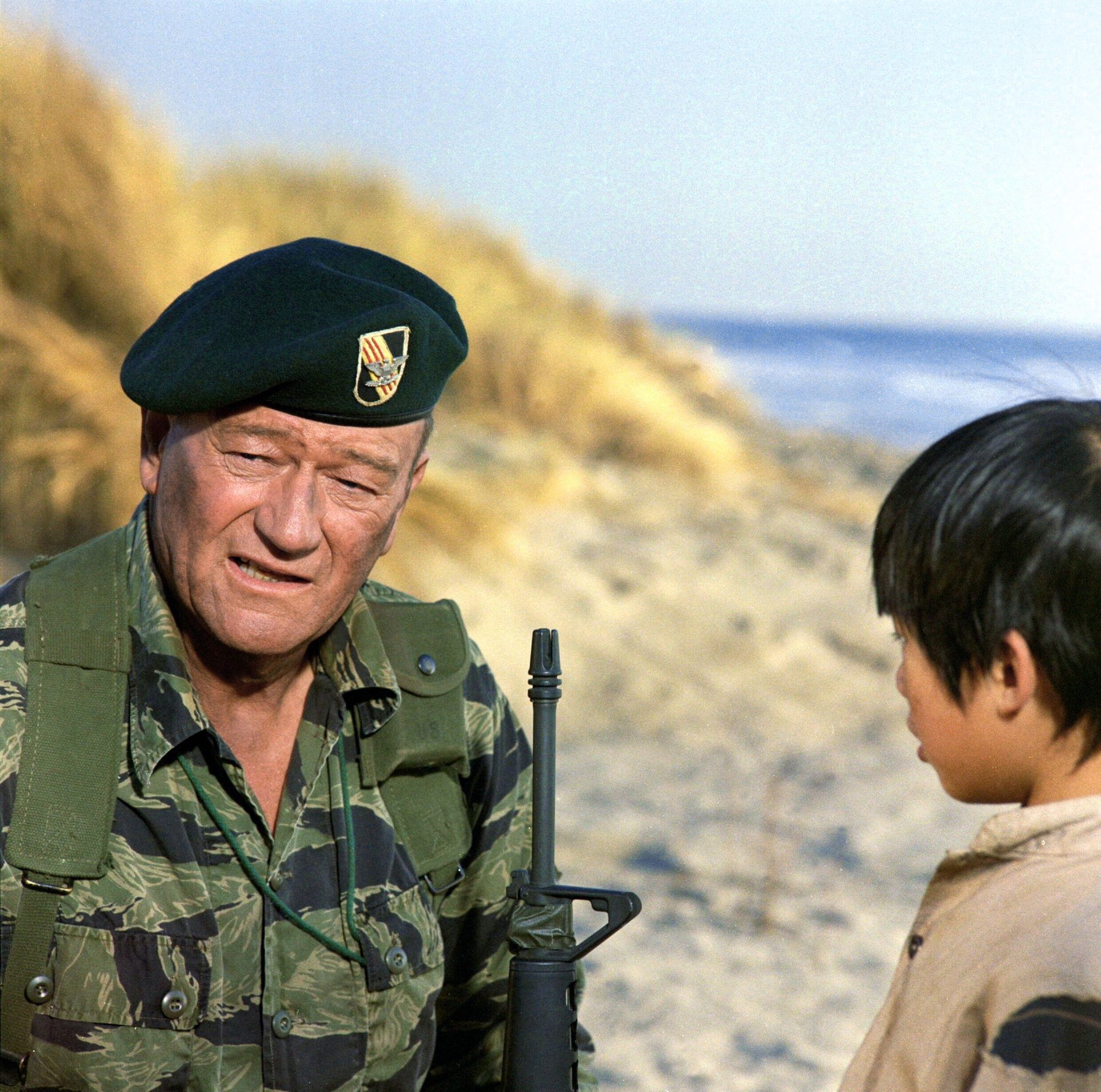 John Wayne as Col. Mike Kirby in 'The Green Berets' in a military uniform holding a gun