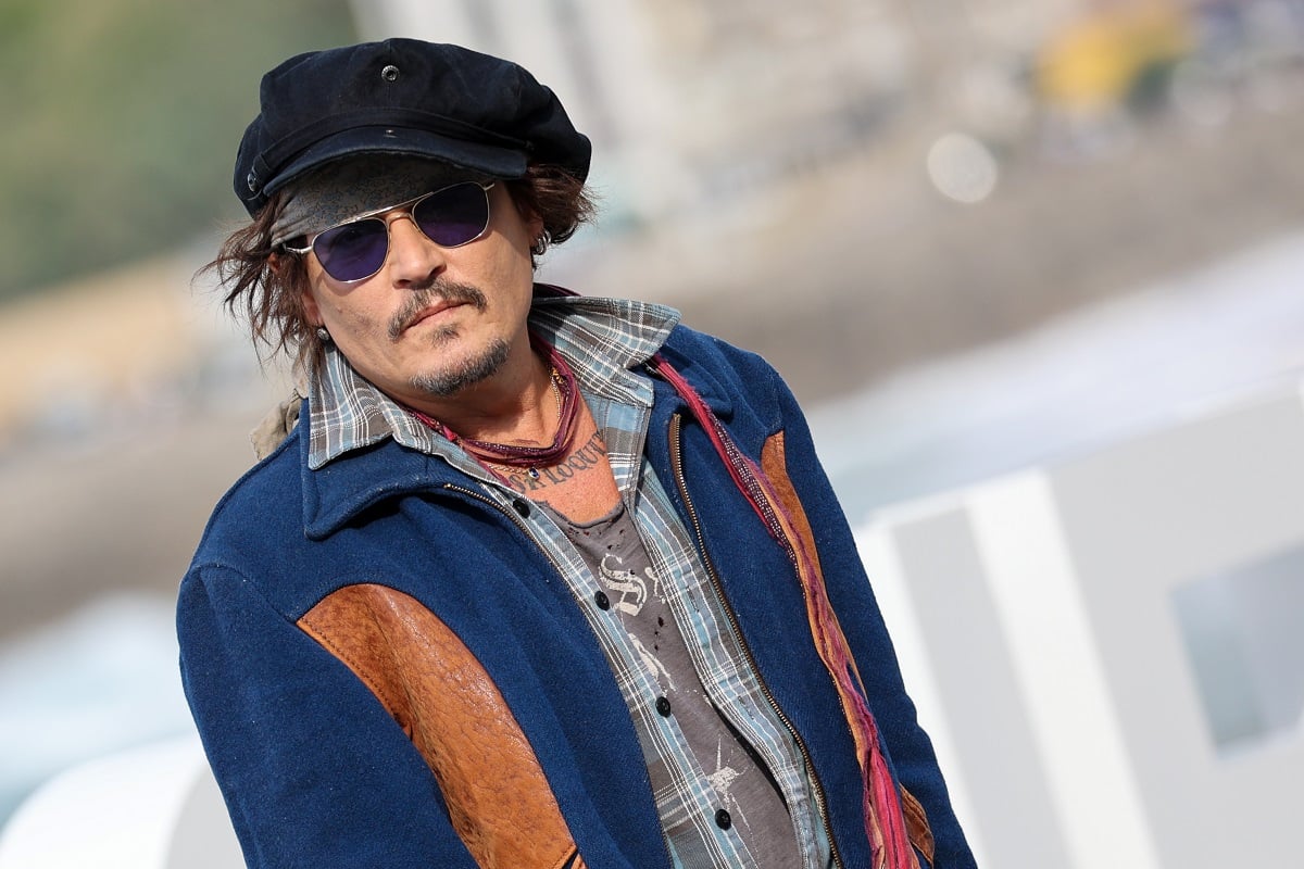 Johnny Depp posing while wearing sunglasses and a blue jacket.