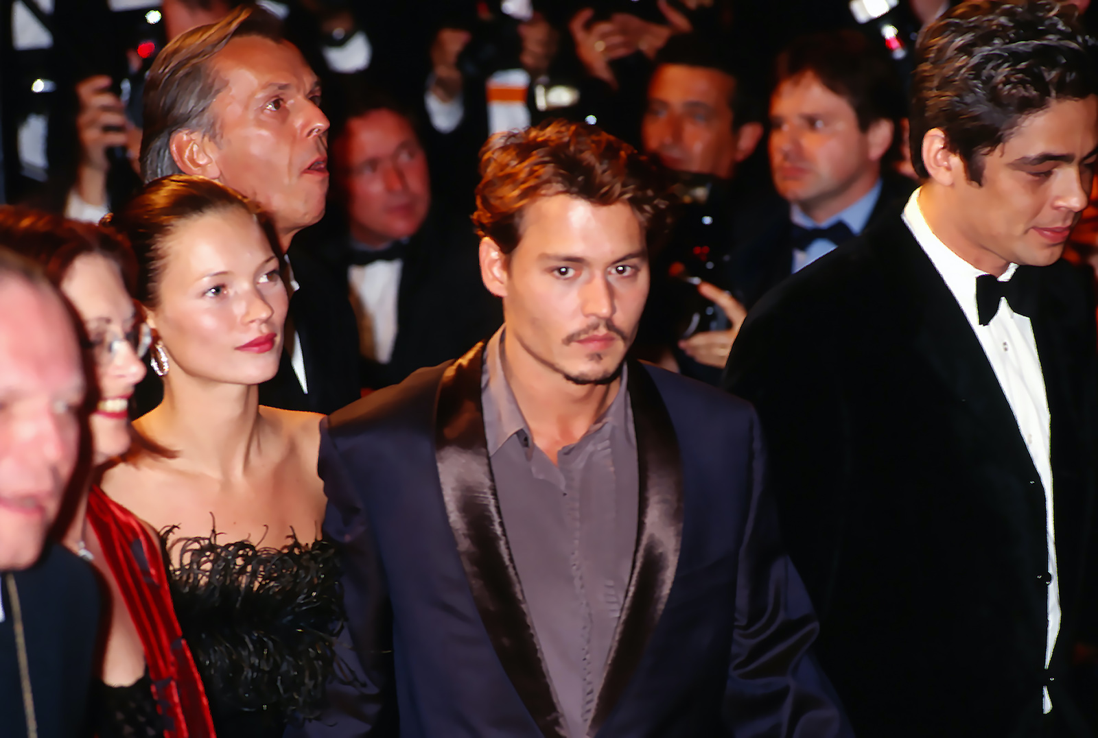 Kate Moss, Johnny Depp, and Benicio Del Toro walk through a crowd in 1998