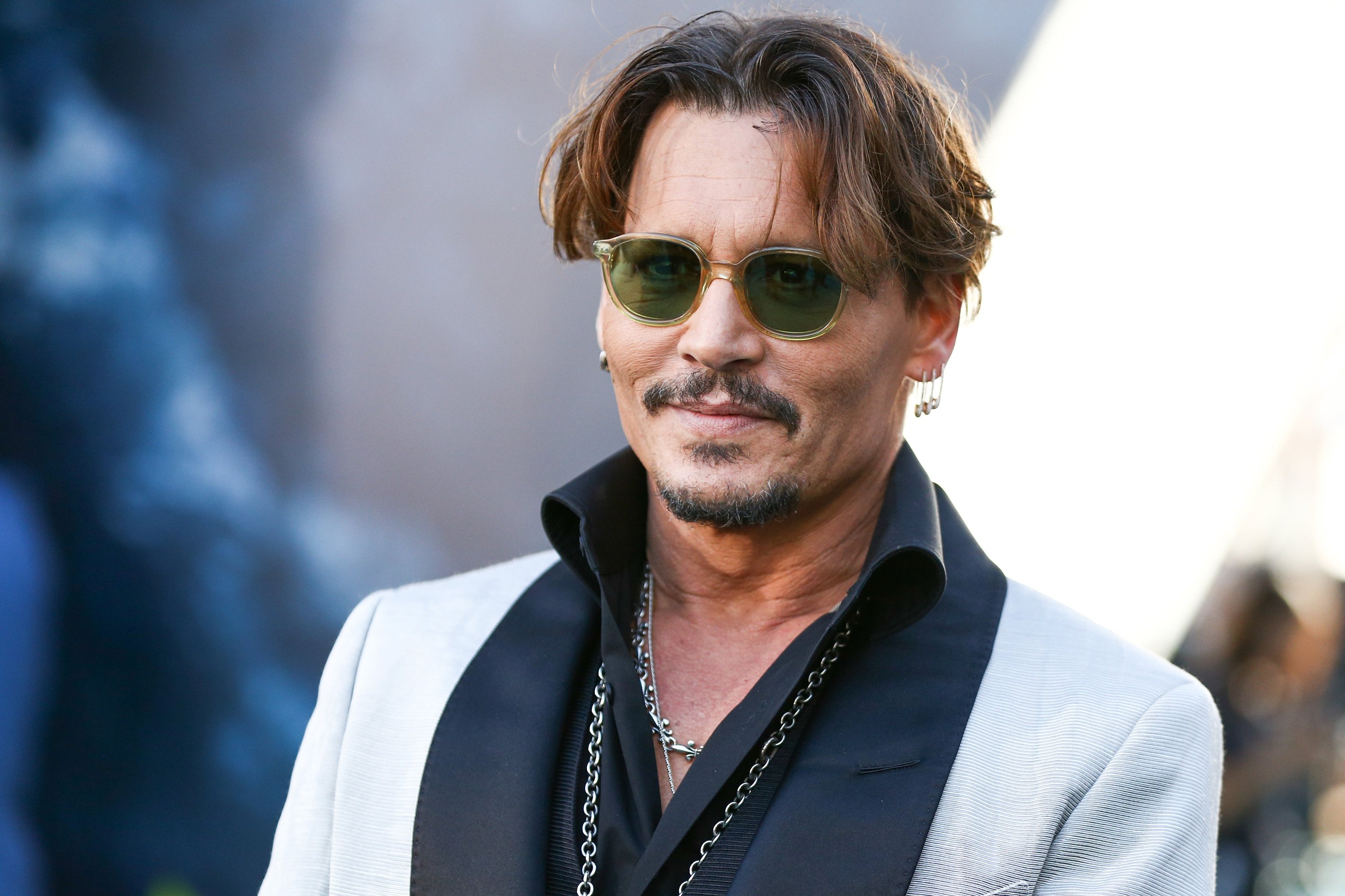Johnny Depp poses at an event while wearing a black and white jacket.