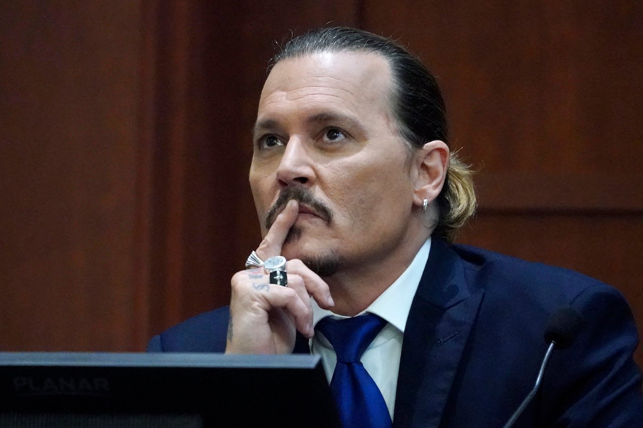 Johnny Depp holds a finger to his mouth in court