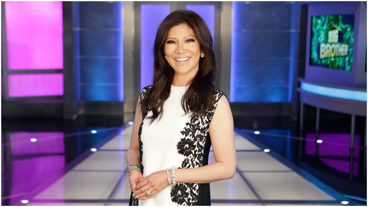 Julie Chen Moonves smiling and standing in front of the Big Brother house