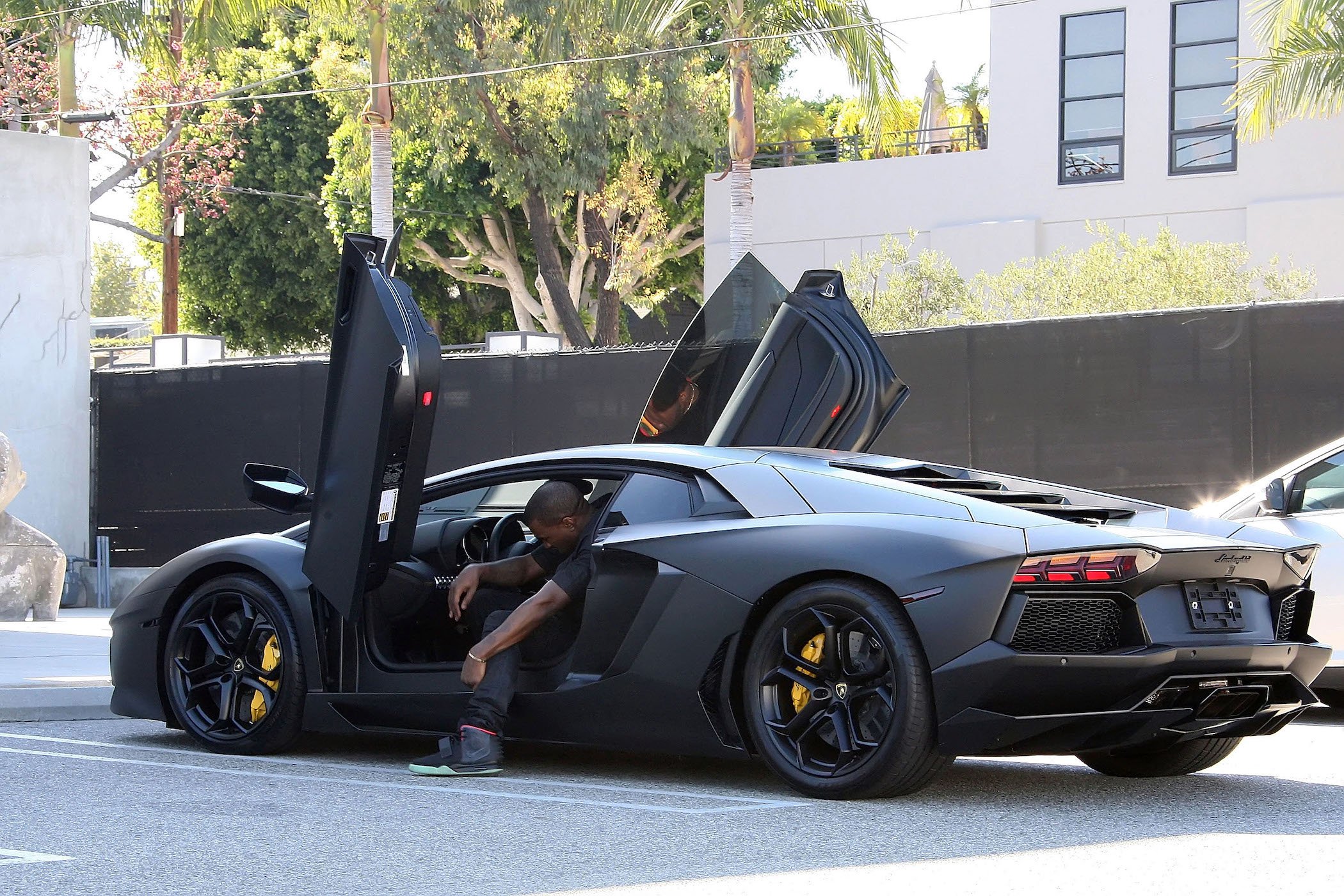Kanye West sitting in a black Lamborghini with the door open in our Kanye West net worth Forbes feature article.