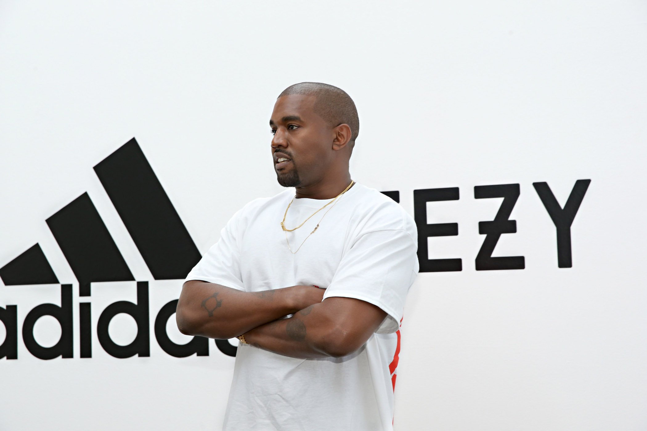 Kanye West in front of an Adidas and Yeezy sign