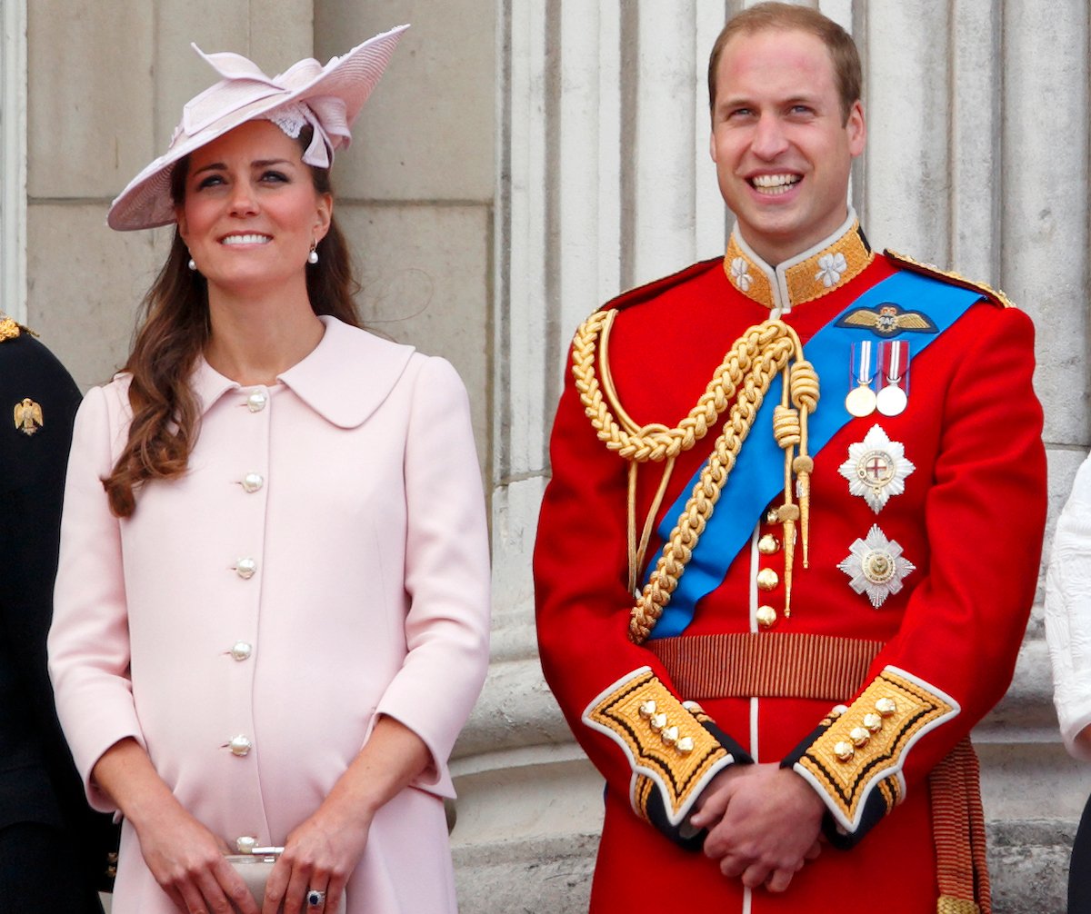 A pregnant Kate Middleton wears pink and she stands next to Prince William on the balcony of Buckingham Palace