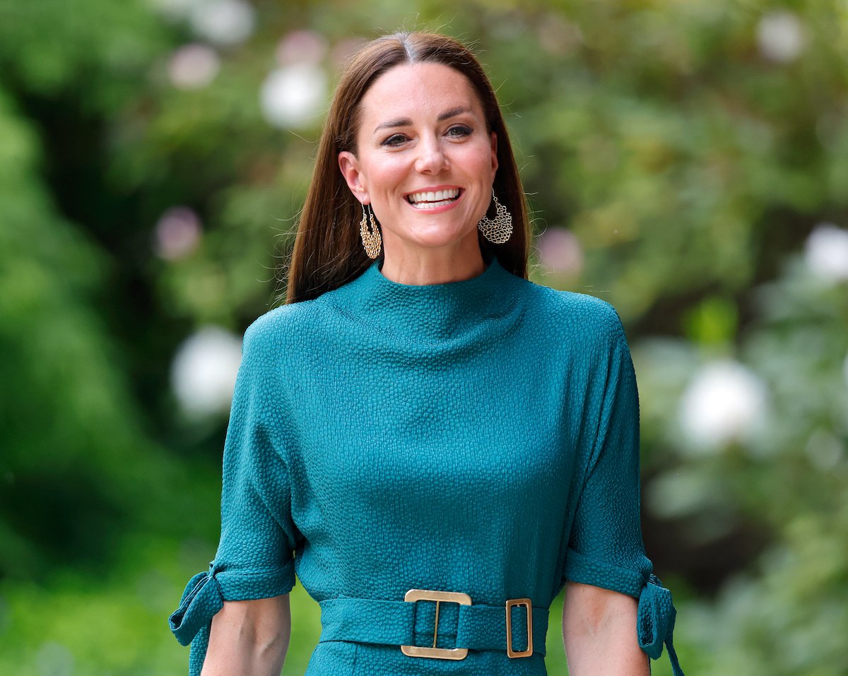 Kate Middleton, whose Prince William breakup made her a 'no-brainer' choice for future queen according to a commentator, smiles wearing a green dress