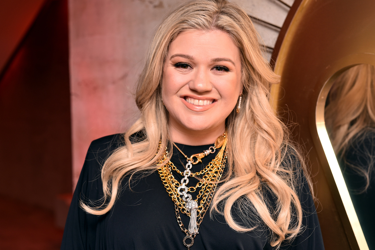 Kelly Clarkson smiling at the camera while wearing a black outfit