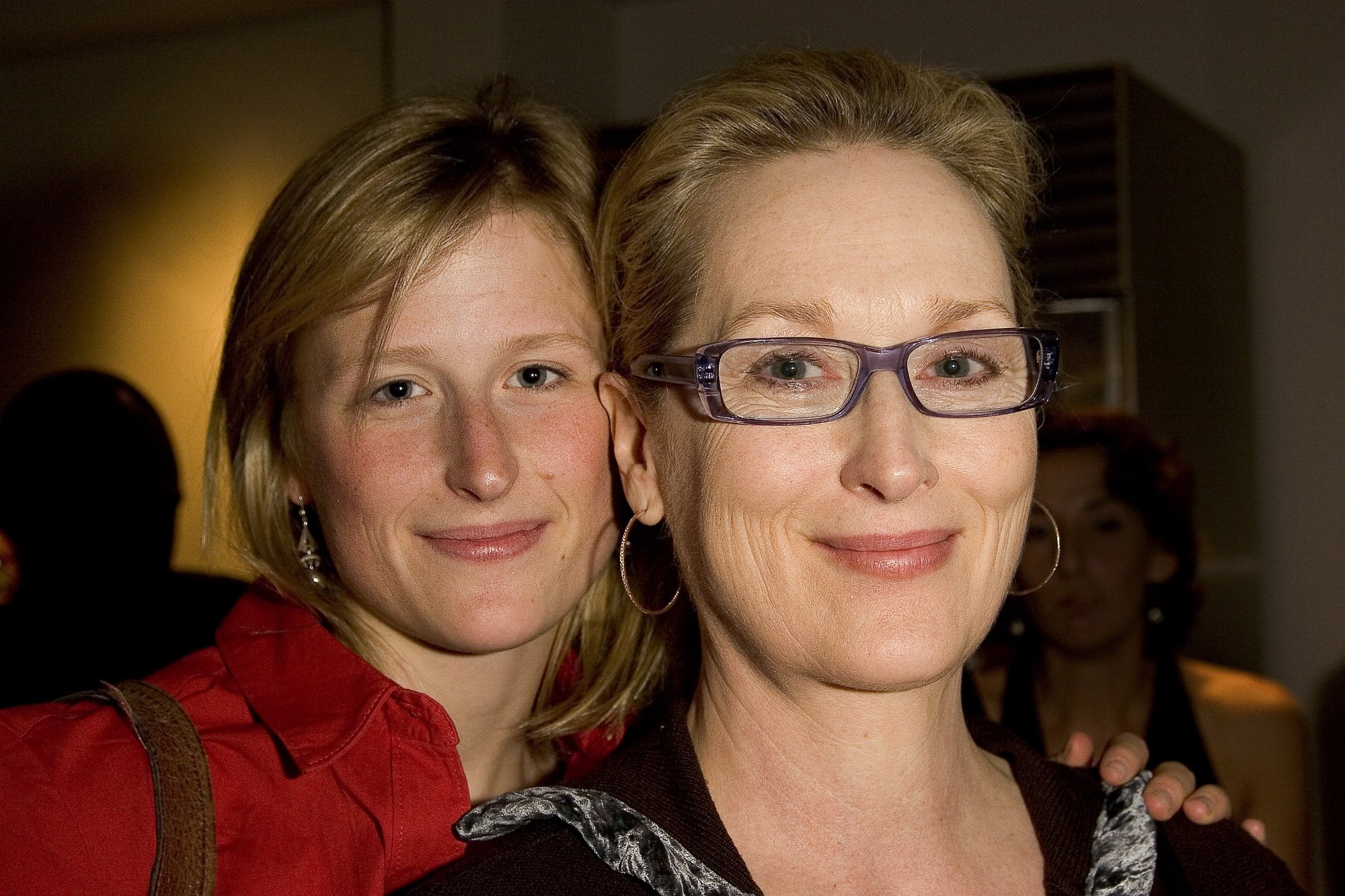 Mamie Gummer and her mother, Meryl Streep, wearing red and black with Mamie's hand on Meryl's shoulder