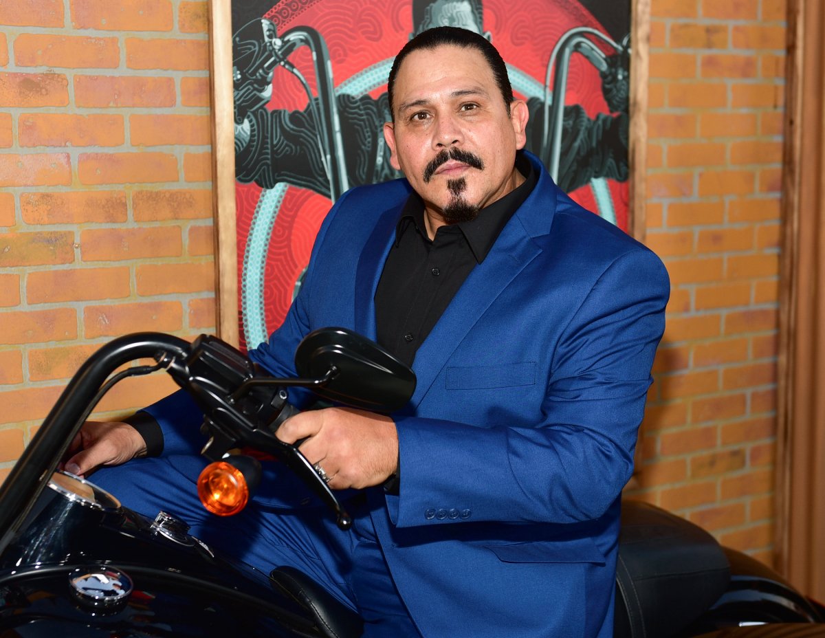 Emilio Rivera plays Alvarez in Mayans MC. He wears a blue suit and black shirt. 