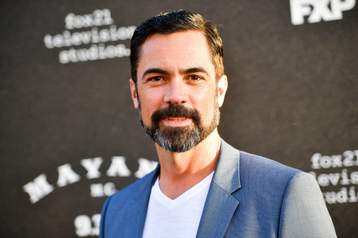Miguel Galindo actor Danny Pino attends the premiere of FX's Mayans M.C. Season 2. Pino is wearing a blue jacket and white shirt. 