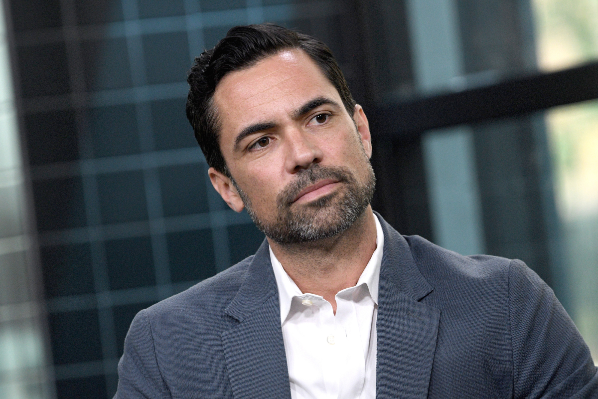 Danny Pino plays Miguel Galindo in Mayans MC Season 4. Pino wears a grey suit jacket and white shirt. 