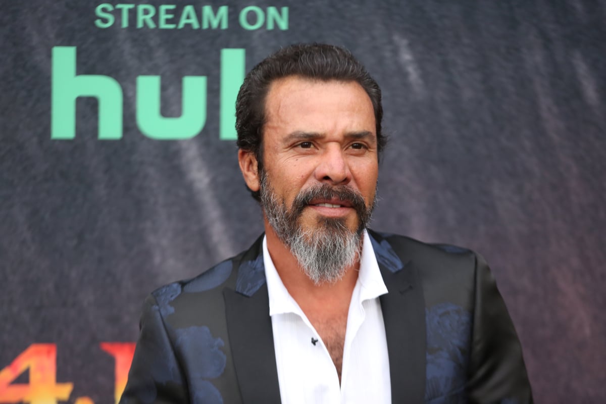Michael Irby attends the Mayans MC Season 4 premiere wearing a white shirt and black and blue jacket. 
