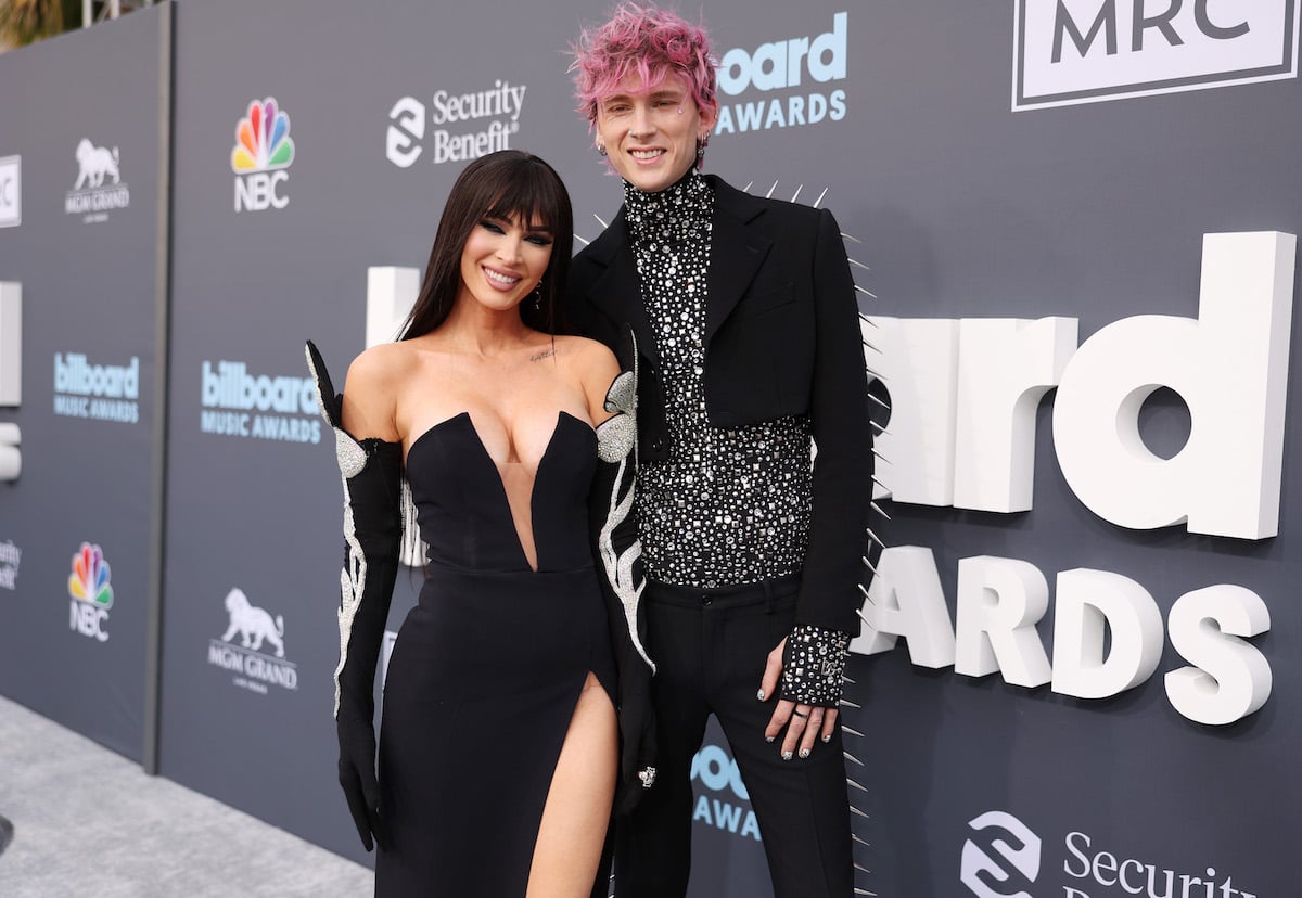 Megan Fox and Machine Gun Kelly pose together in matching outfits at an event.