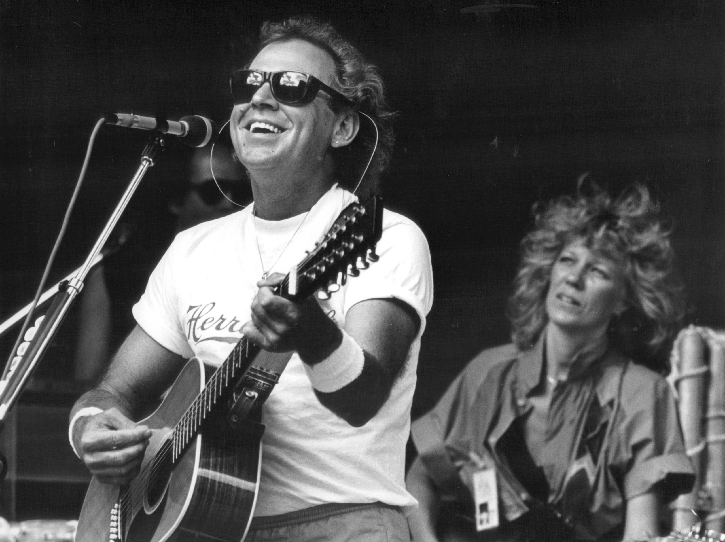 Jimmy Buffett playing songs with a guitar