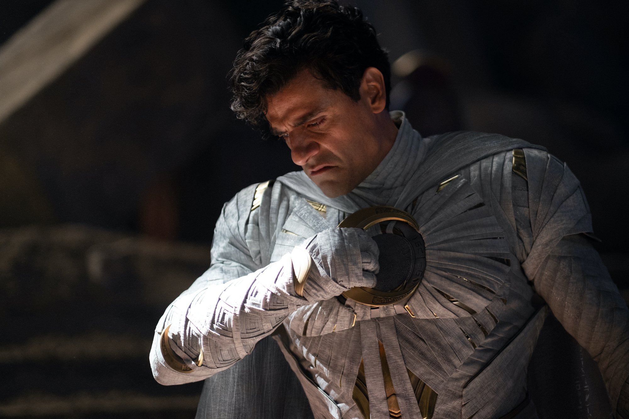 Oscar Isaac as Marc Spector in 'Moon Knight' Episode 6. He's wearing his Moon Knight costume and holding the sickle he throws.