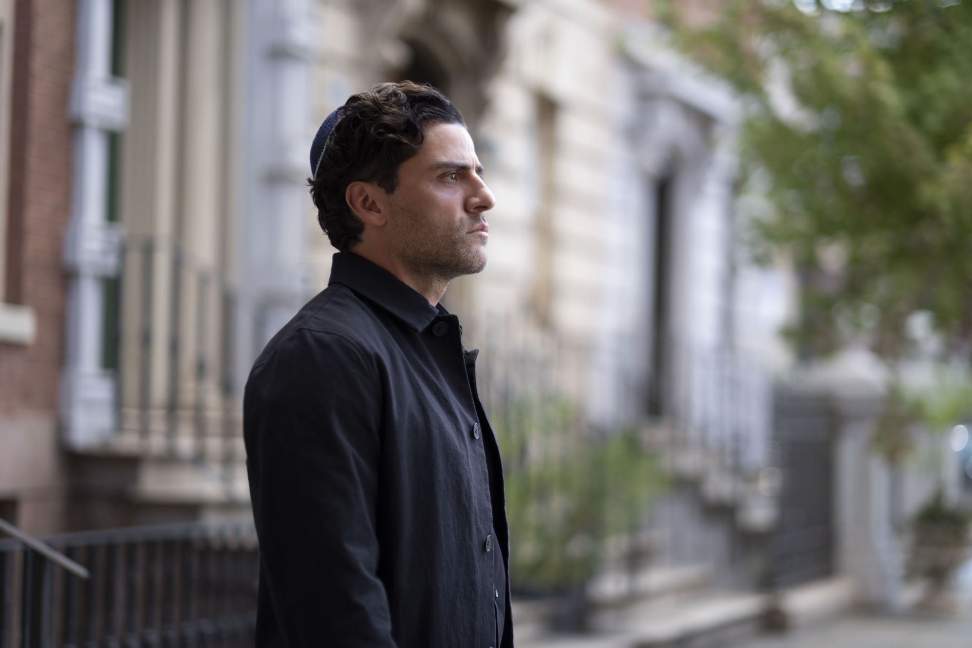 Oscar Isaac as Marc Spector in 'Moon Knight' on Disney+, which almost featured a ‘Hawkeye’ character, wears a dark gray jacket and a blue kippah.