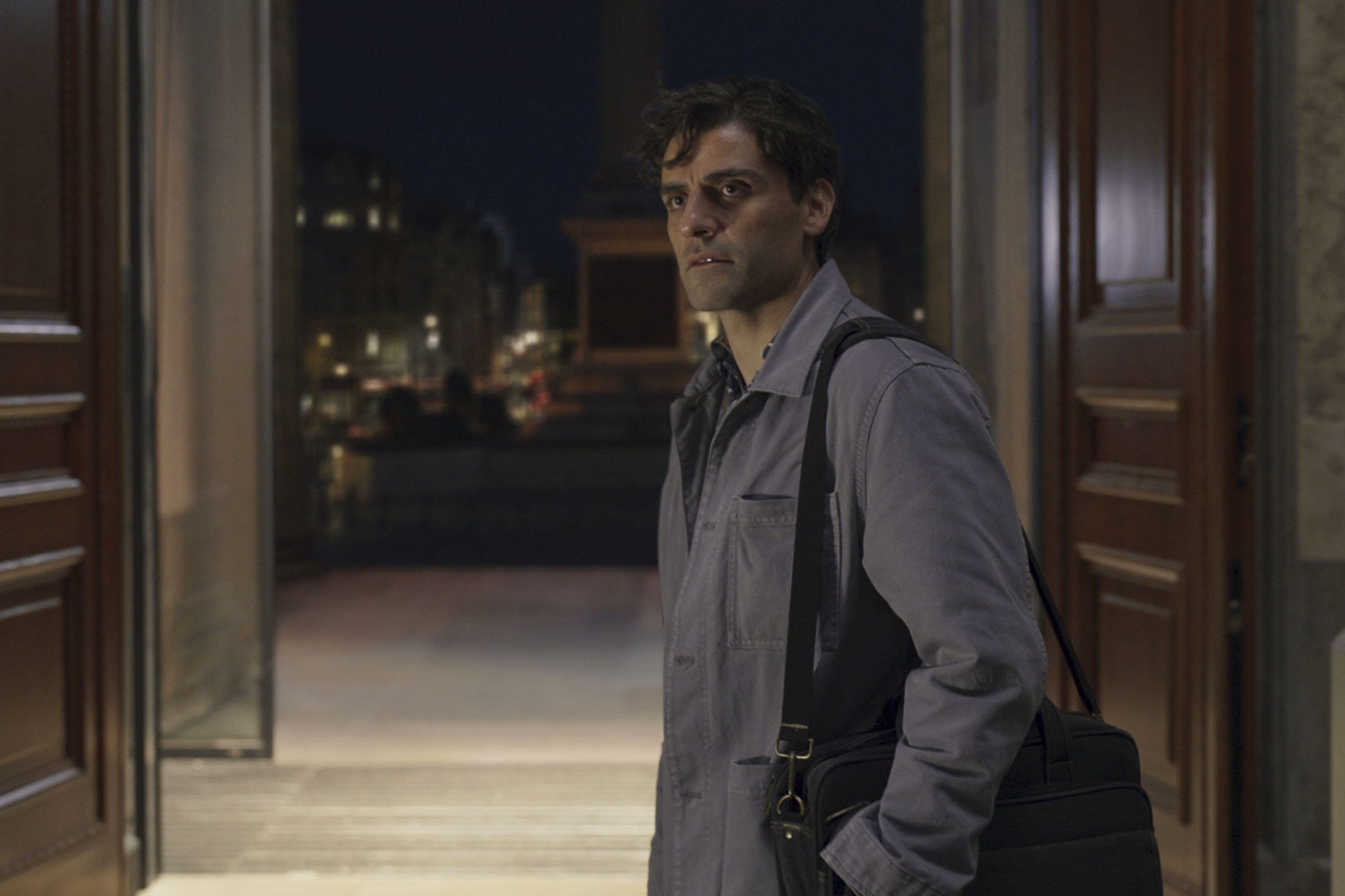 Oscar Isaac, whose 'Moon Knight' character is a part of the Midnight Sons in the comics, wears a light gray jacket and a black bag, in character as Steven Grant.