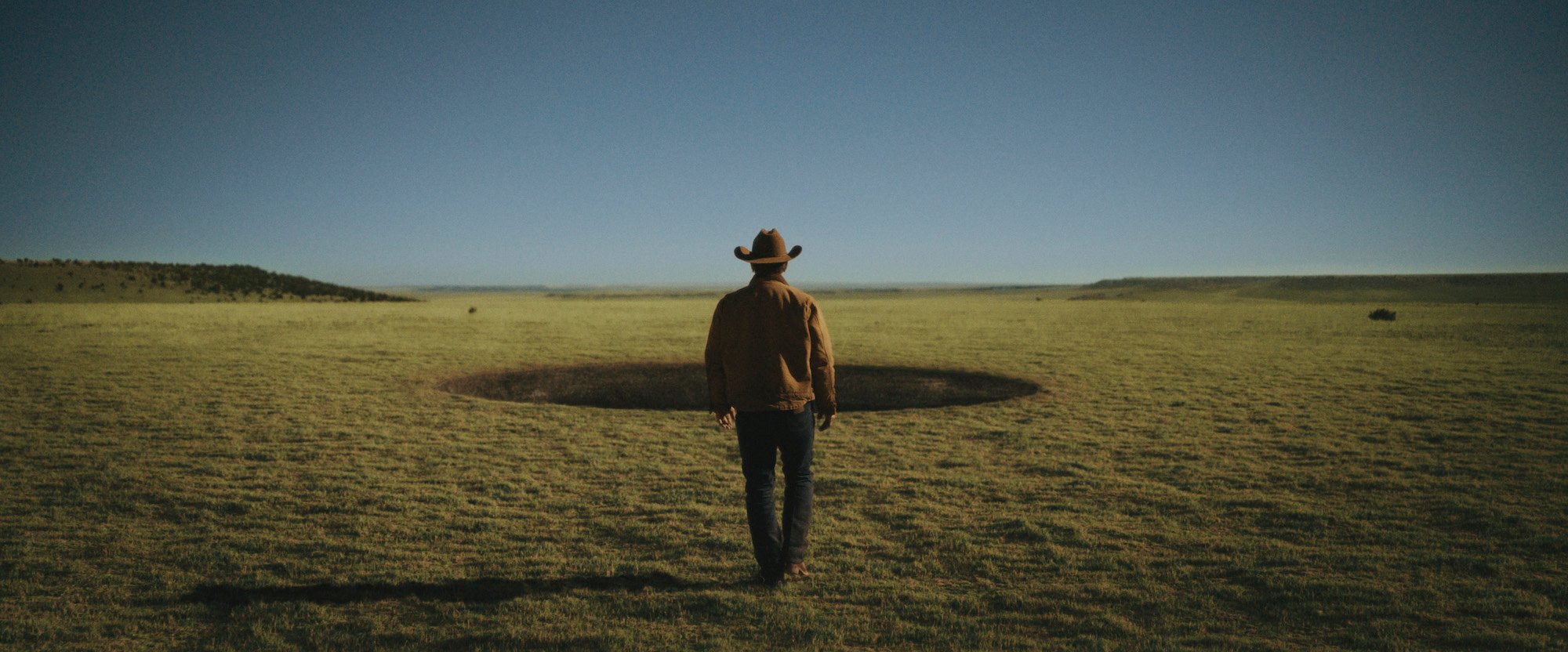 'Outer Range' star Josh Brolin stares out at the mysterious hole that appears on his property in a production still from season 1.