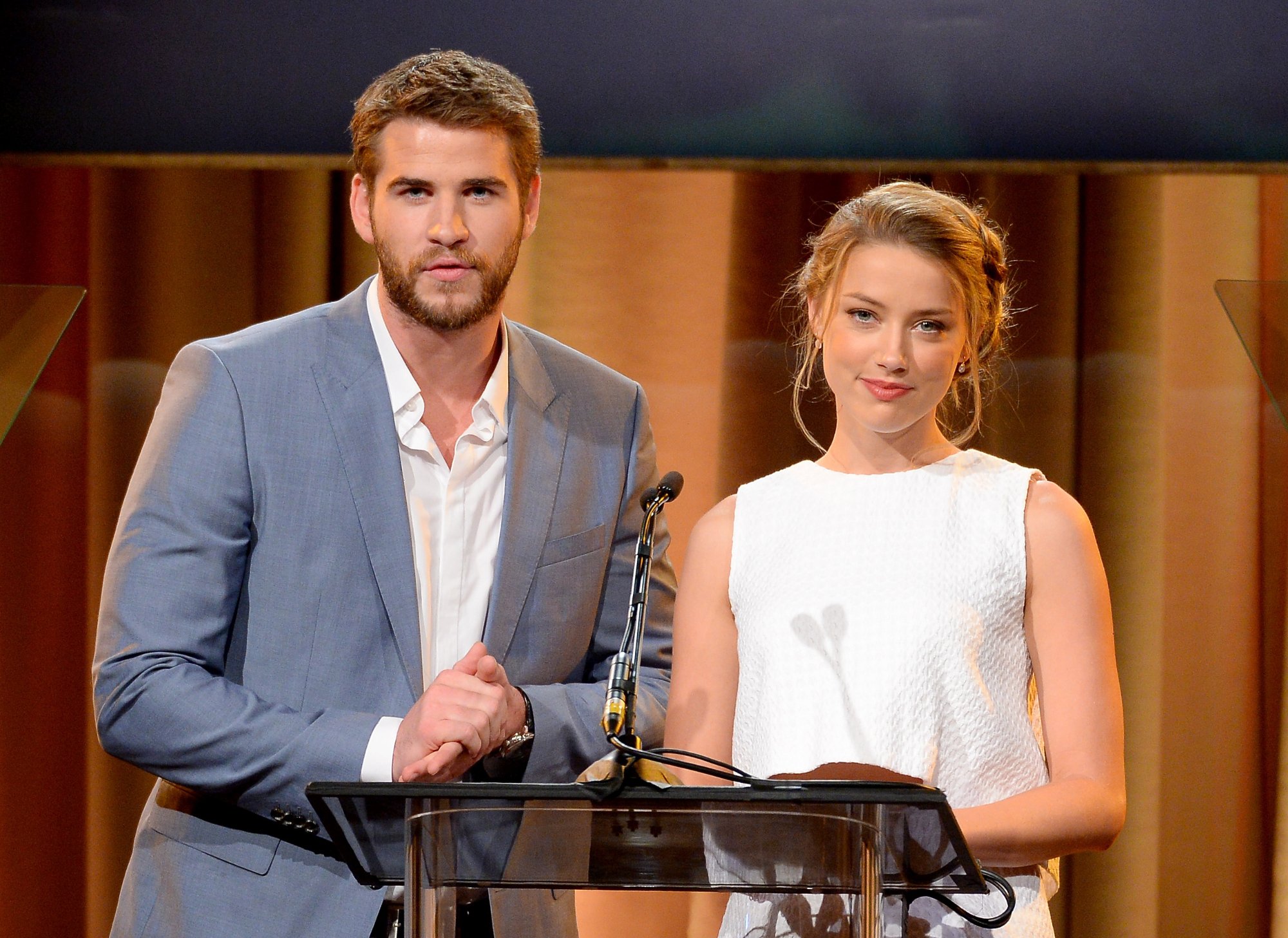 'Paranoia' actors Liam Hemsworth and Amber Heard standing at the microphone behind a podium at the Hollywood Foreign Press Association's 2013 Installation Luncheon