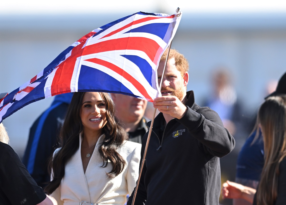 Prince Harry and Meghan Markle, who reportedly never wanted to be on the balcony during the queen's Platinum Jubilee, hold flag at Invictus Games event