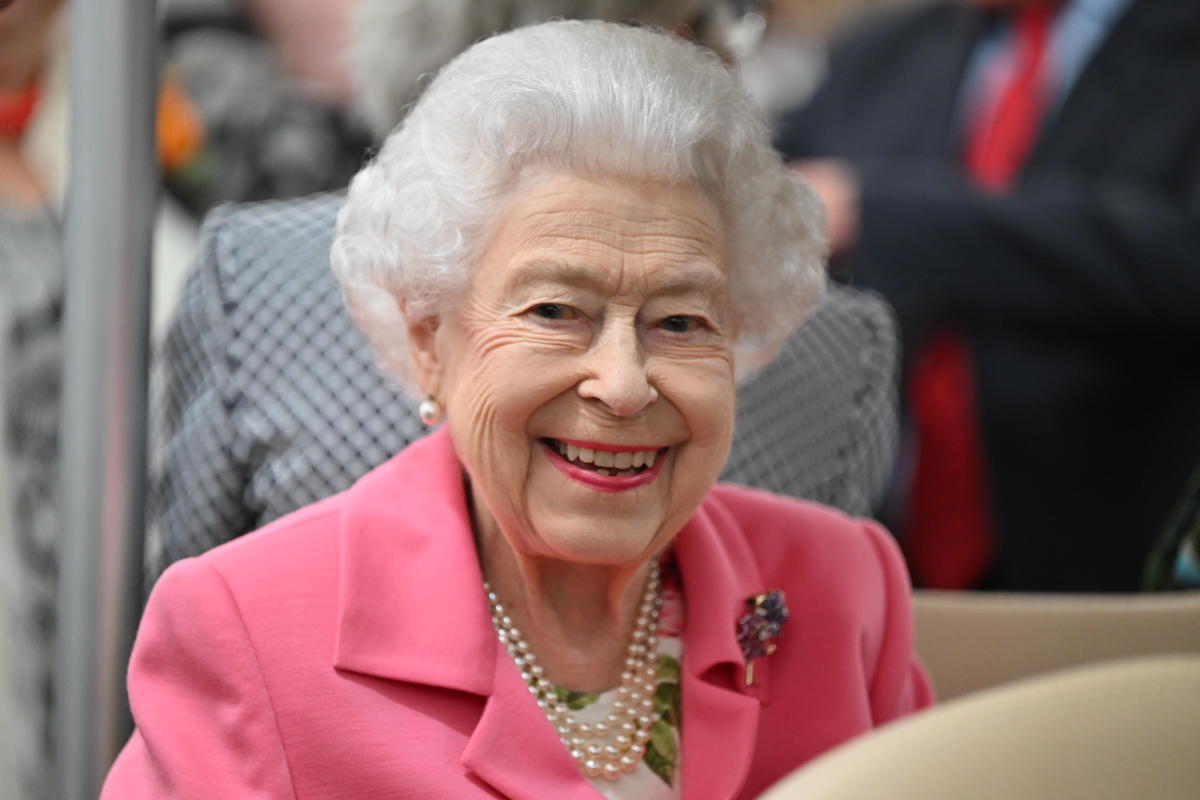 Queen Elizabeth II, whose Platinum Jubilee Weekend includes a four-day celebration, smiles wearing a pink blazer