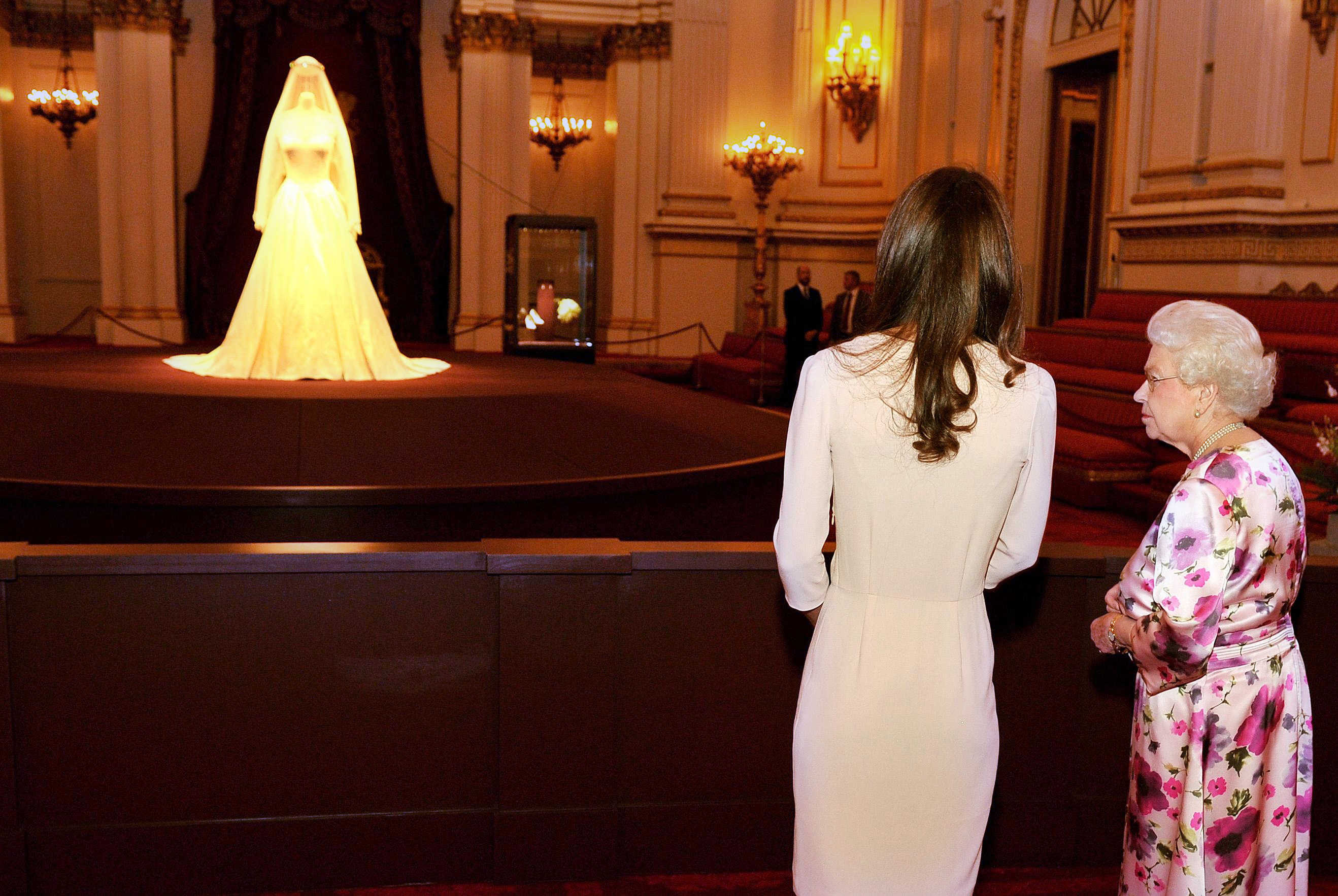 Queen Elizabeth II talks with Kate Middleton at a Buckingham Palace exhibition as they view the dress the duchess wore for her royal wedding to Prince William