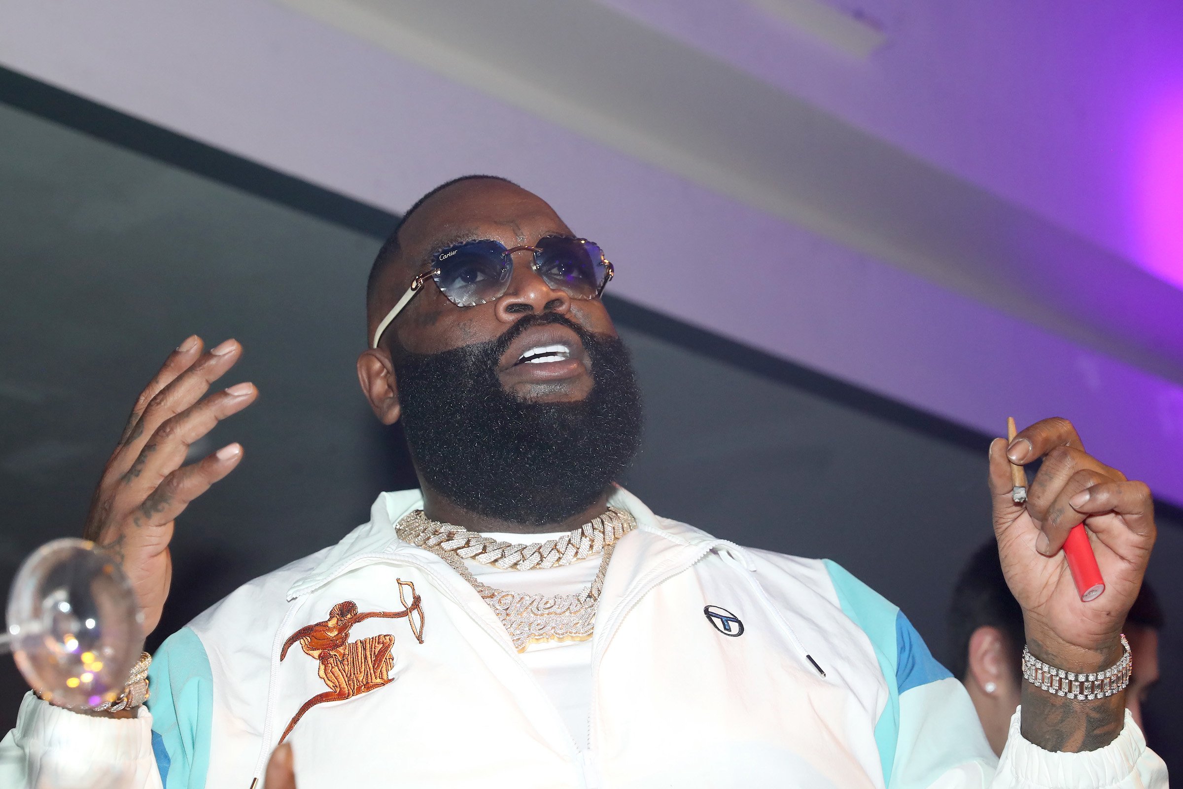 Car collector Rick Ross wearing a white jacket and smoking