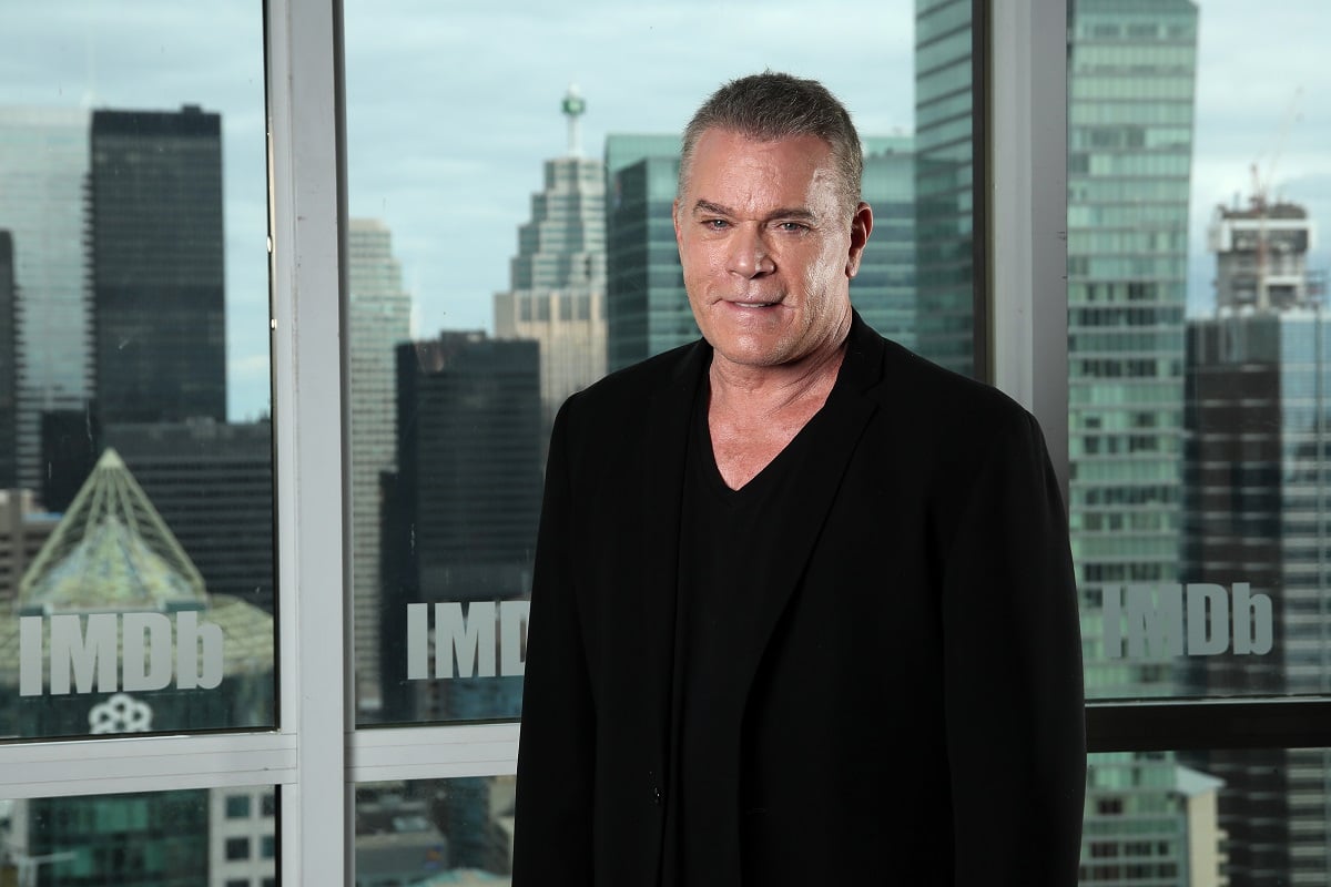 Ray Liotta smiling while wearing an all black suit.