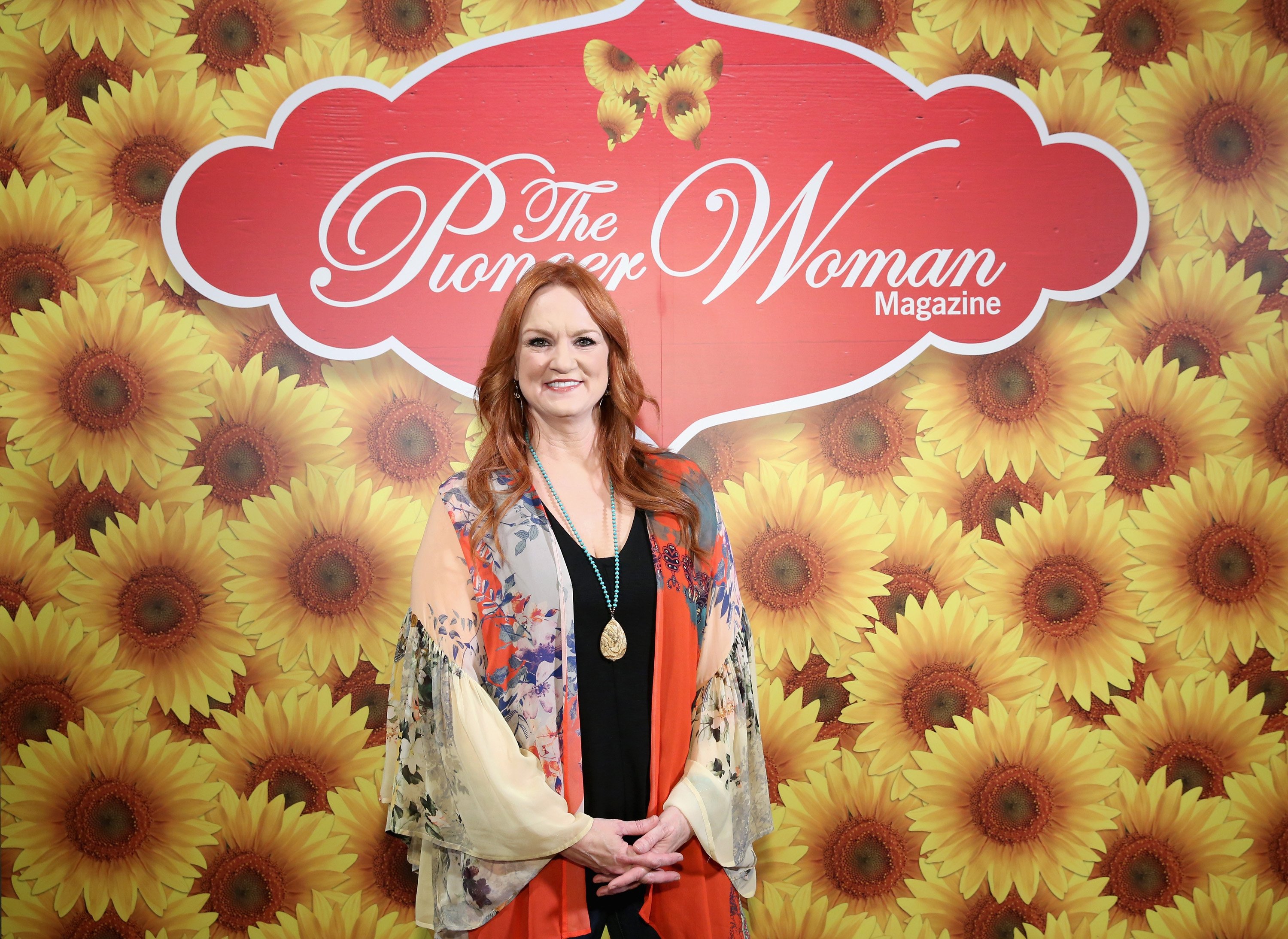 The Pioneer Woman Ree Drummond stands in front of a flower wall during an event. 