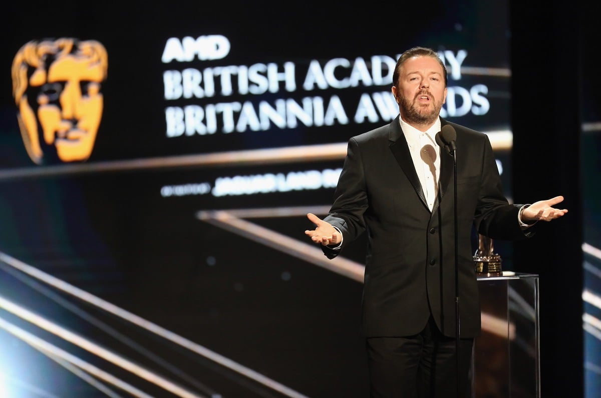 Ricky Gervais talking while on stage in front of a microphone.