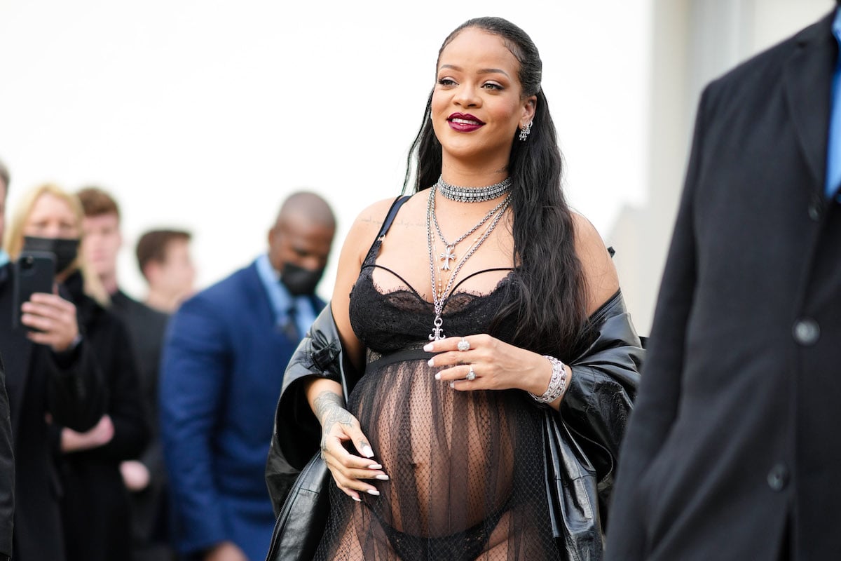 Rihanna shows off her baby bump in a sheer black dress at an event.