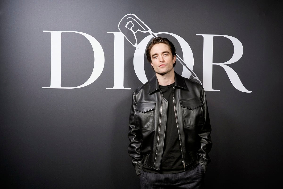 Robert Pattinson posing while wearing a black leather jacket.