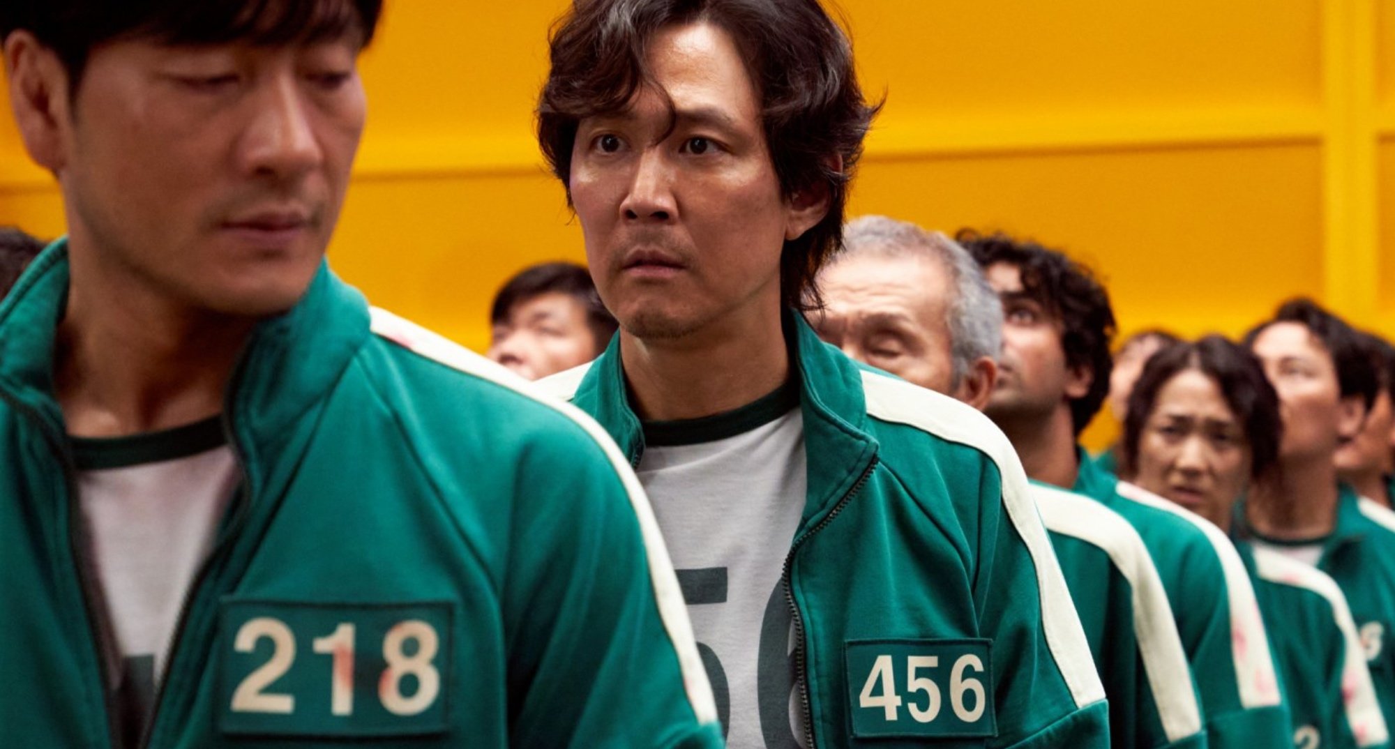 Sang-woo and Gi-hun in 'Squid Game' wearing numbered player jackets.