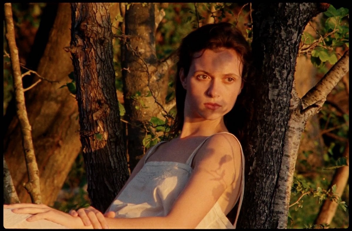 Juliette Jouan as Juliette laying against a tree in a white dress in 'Scarlet'
