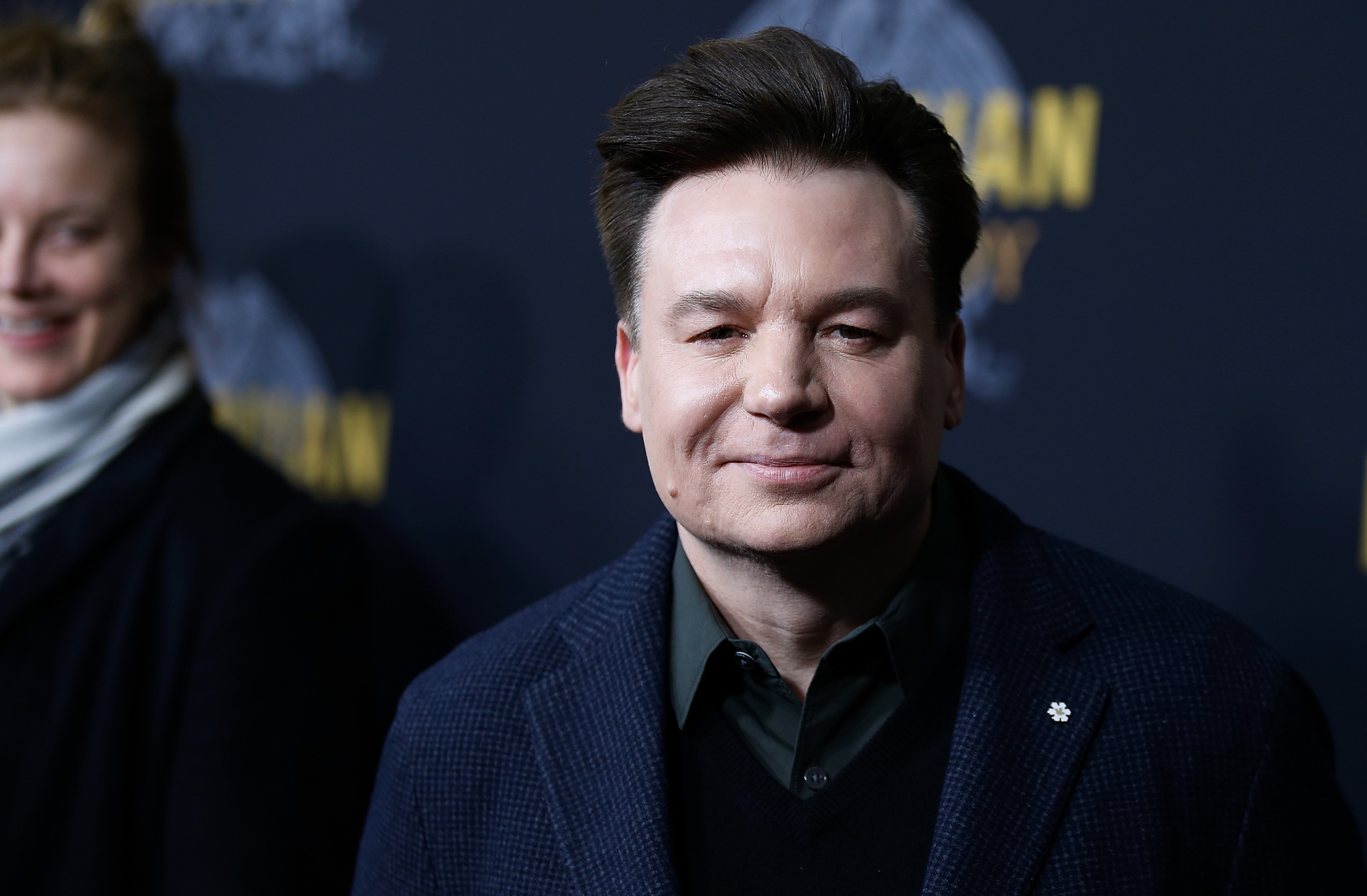 'Shrek' star Mike Myers wearing a jacket and collared shirt in front of a step and repeat