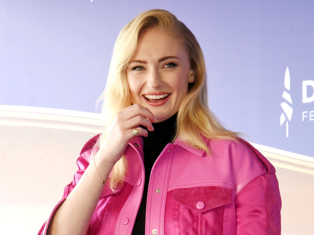 Sophie Turner, who is expecting her second baby, wearing a pink jacket and smiling