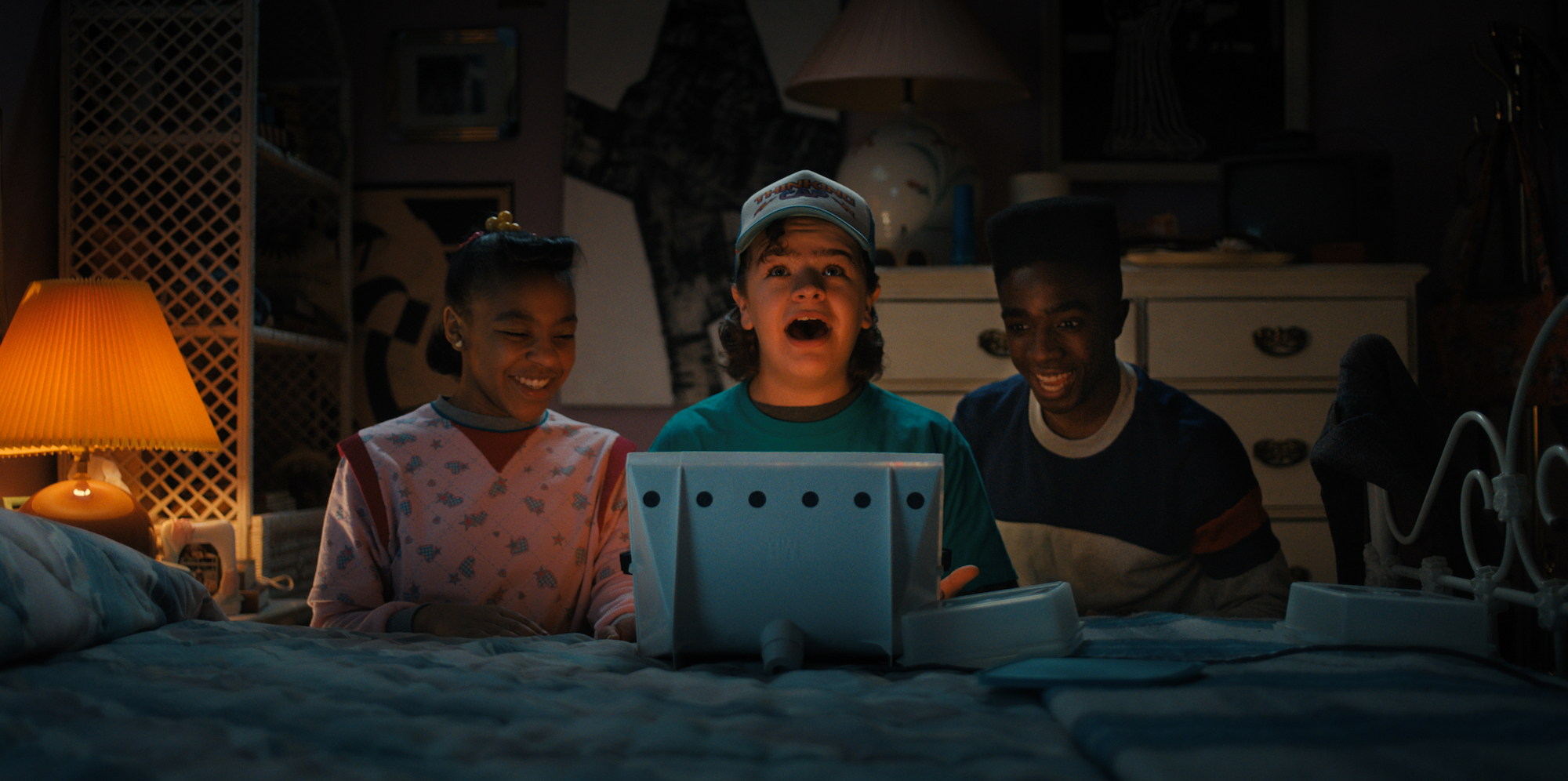 Priah Ferguson, Gaten Matarazzo, and Caleb Mclaughlin in front of a Lite Brite in a production still from "The Massacre at Hawkins Lab"