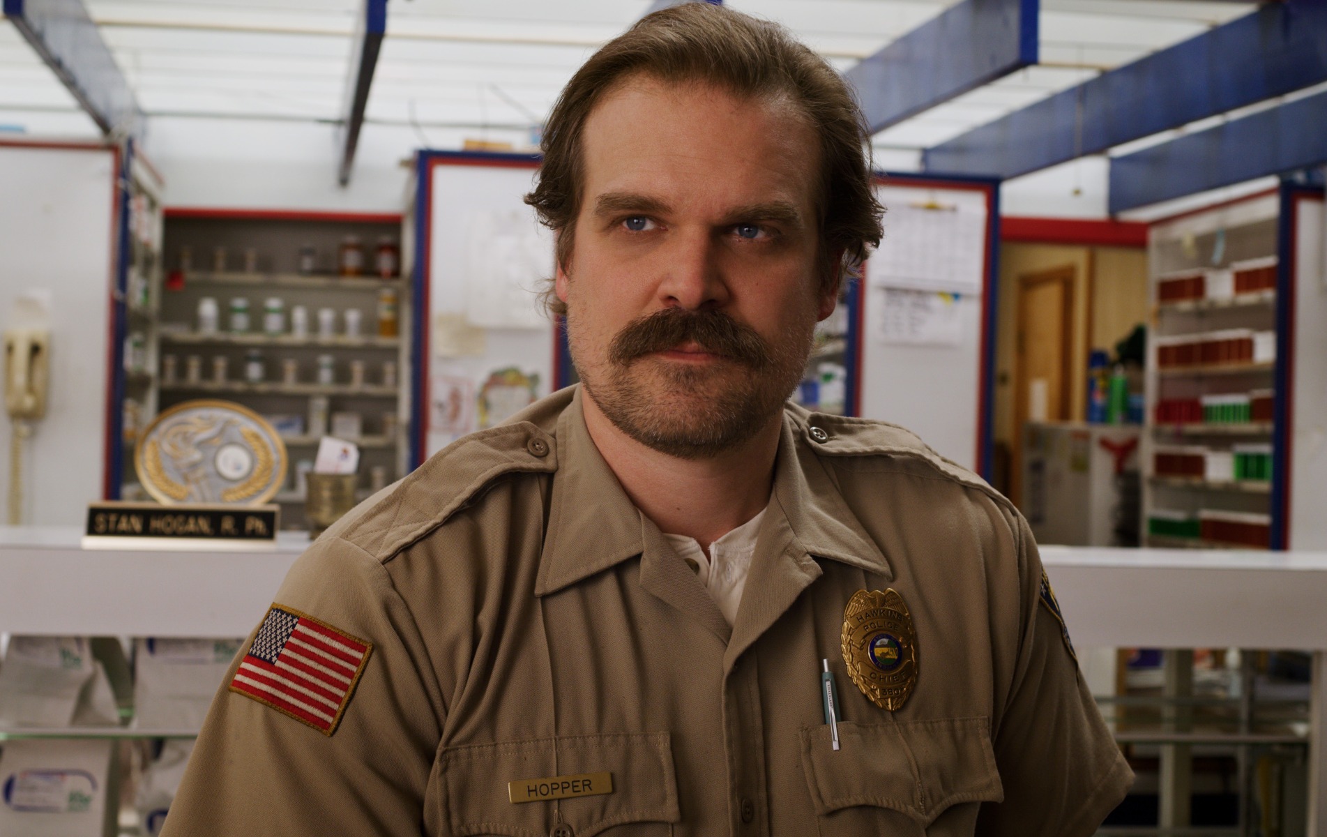 'Stranger Things' star David Harbour as Jim Hopper, whose ending is reportedly 'quite moving.' He's wearing his police uniform here and standing in a store.