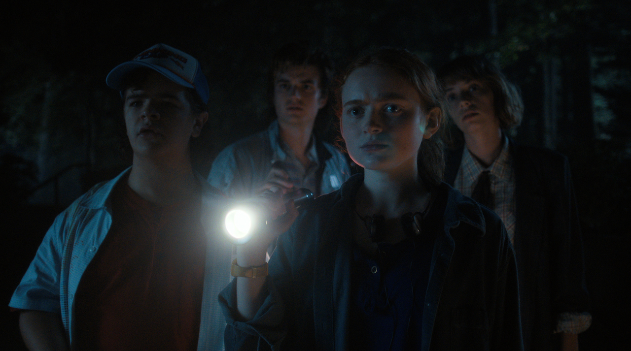 Dustin, Steve, Max, and Robin walk through the woods in 'Stranger Things' Season 4. 