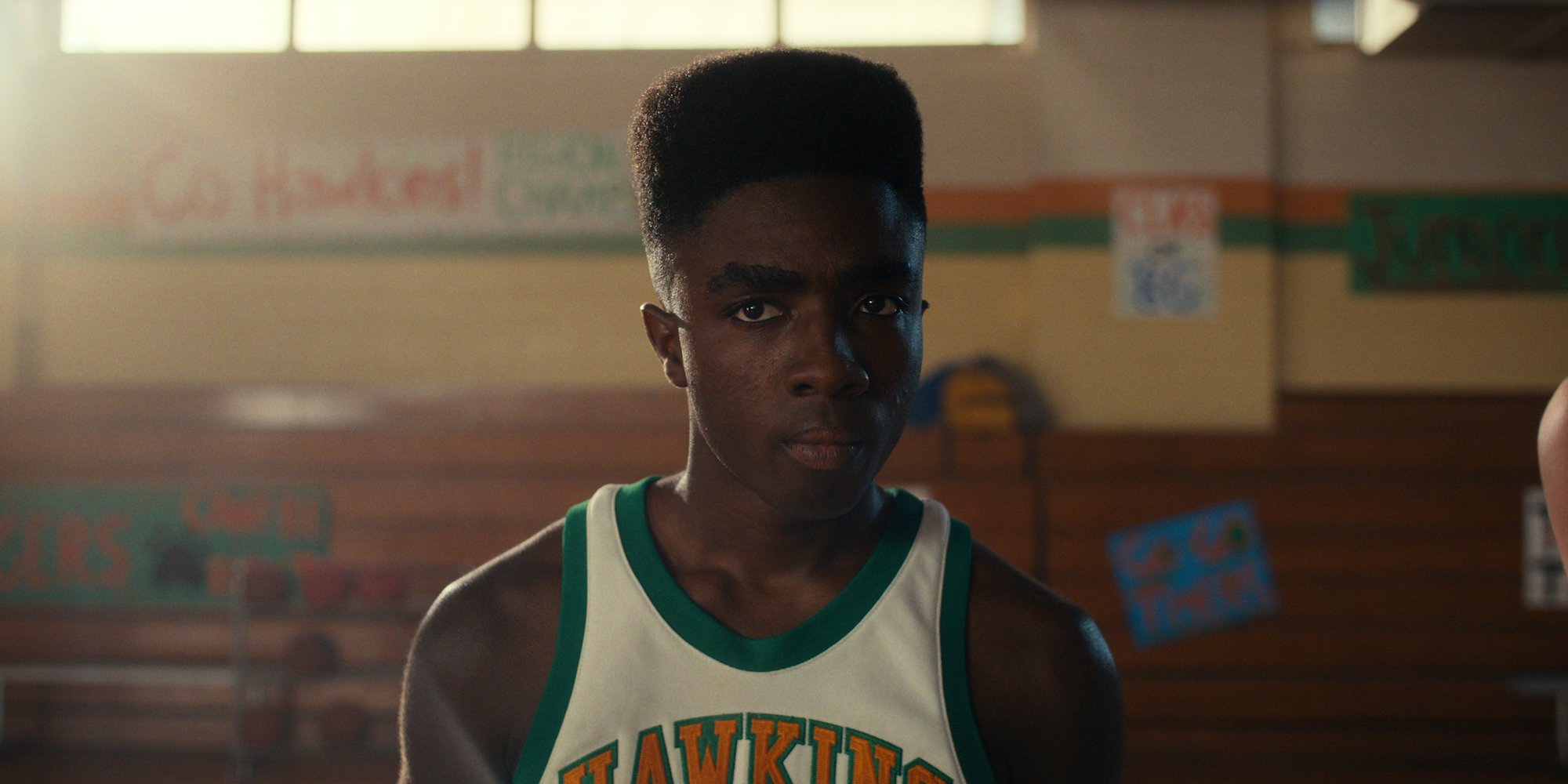 Caleb McLaughlin as Lucas wearing a Hawkins basketball jersey.